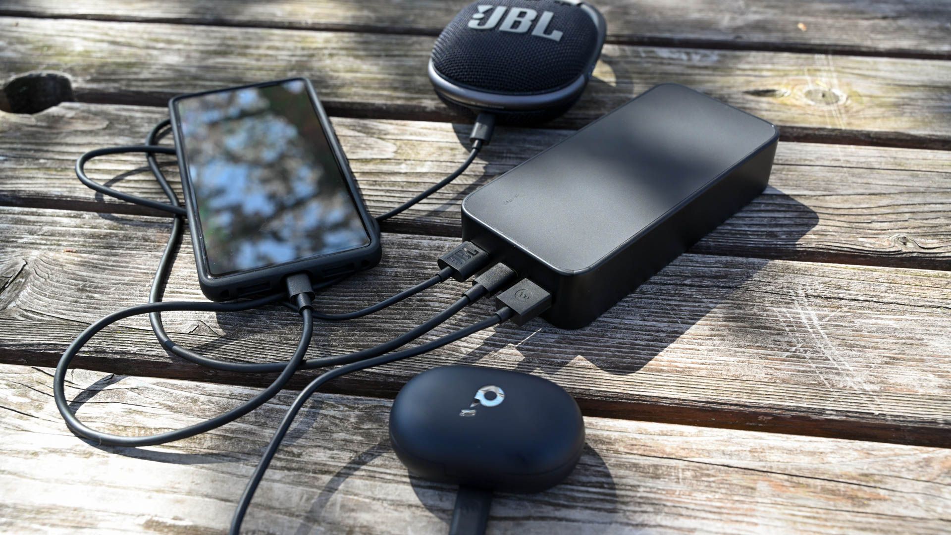Charging three devices at once on a picnic table using the Mophie Powerstation XL.