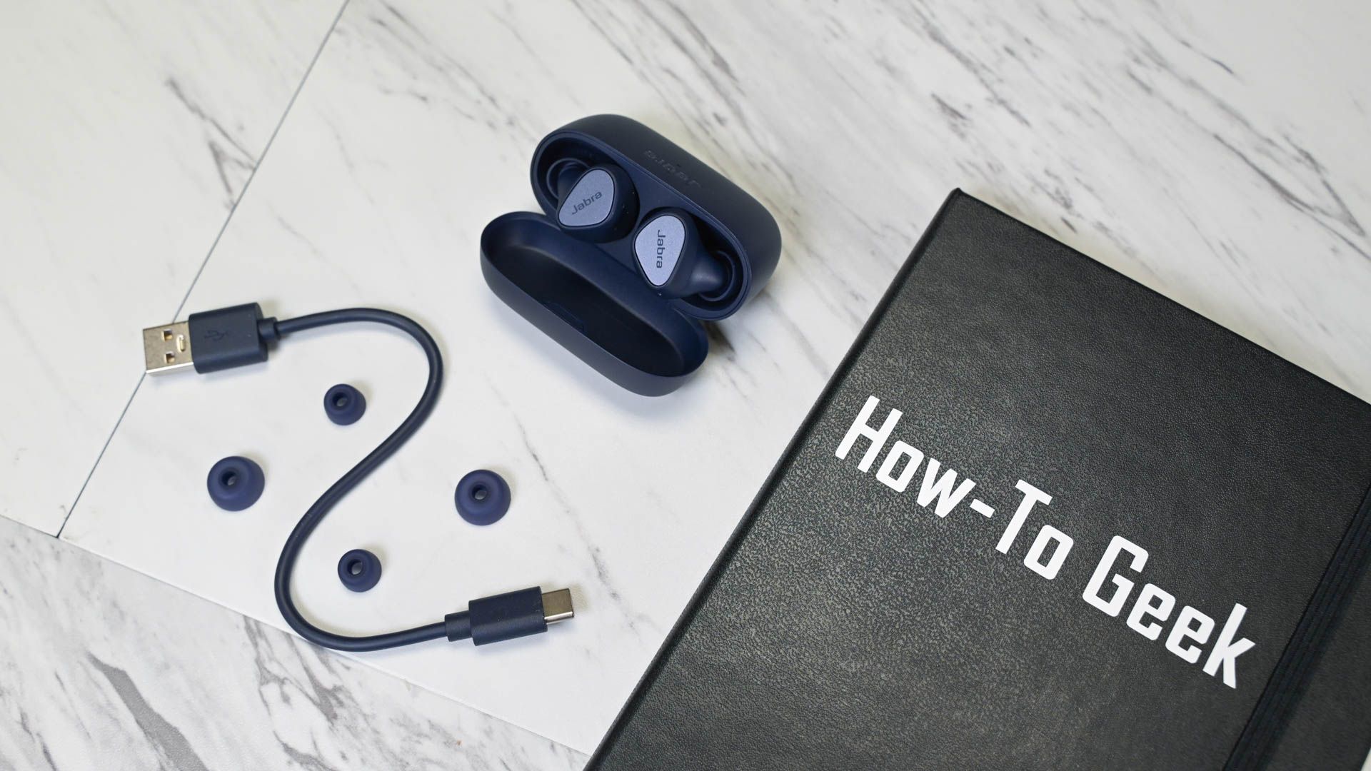 Jabra Elite 4 ear tips and cable next to a HTG notebook