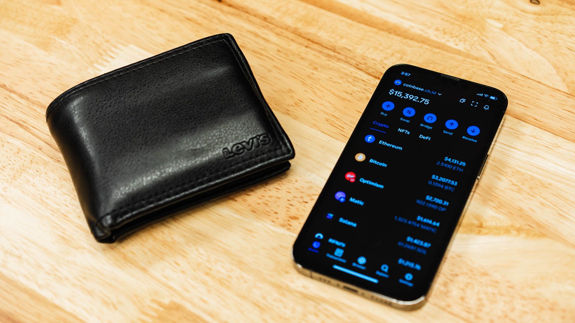 Coinbase app open on an iPhone next to a wallet