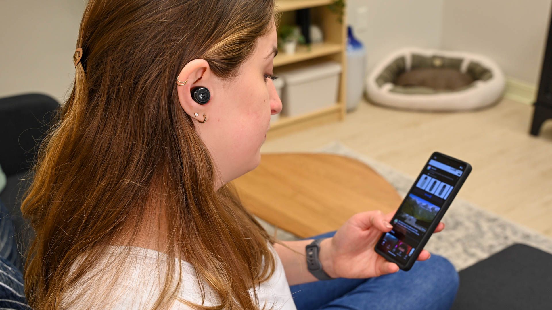 Person using the the JBL Quantum TWS Air earbuds with a phone