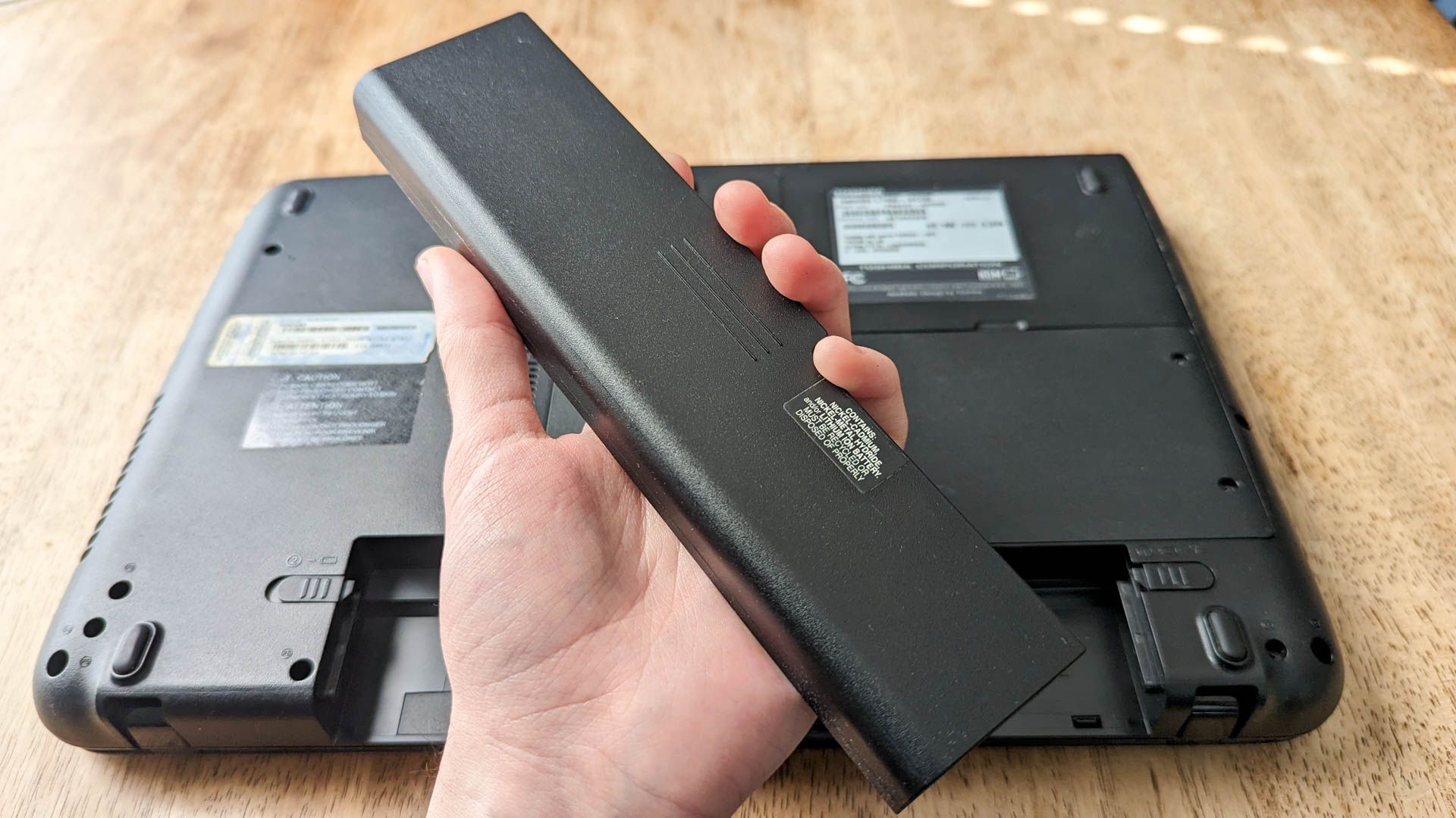 Person holding a removable laptop battery
