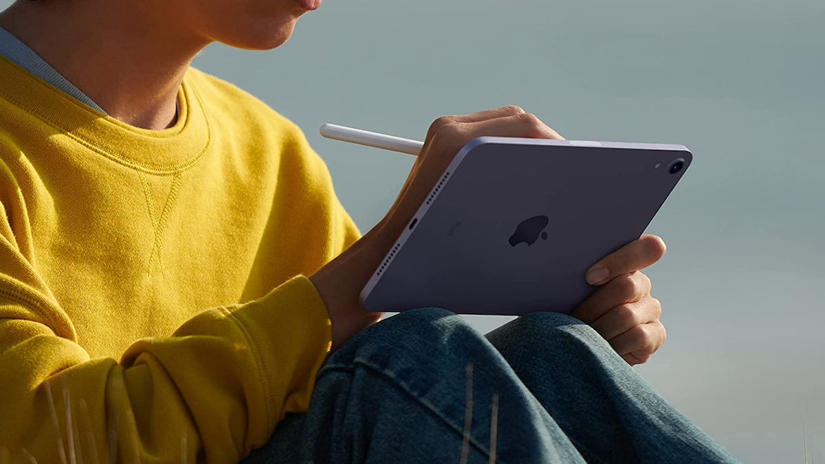 Person in a yellow shirt using an Apple tablet with a stylus pen.