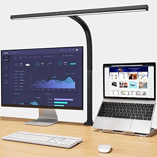 A lamp placed on a computer desk with a laptop, monitor, keyboard, and mouse.