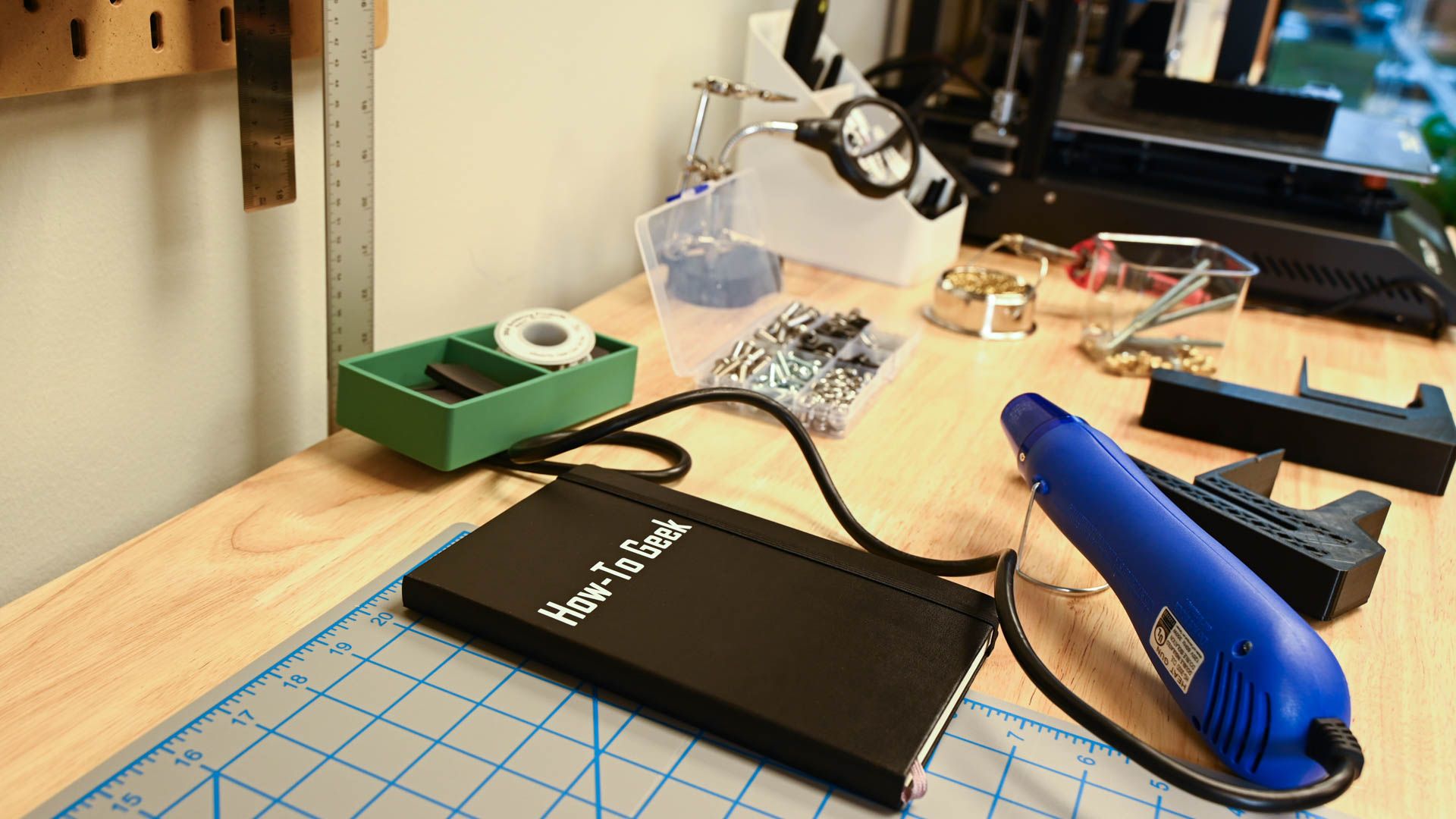 A How To Geek Notebook on a workbench with tools