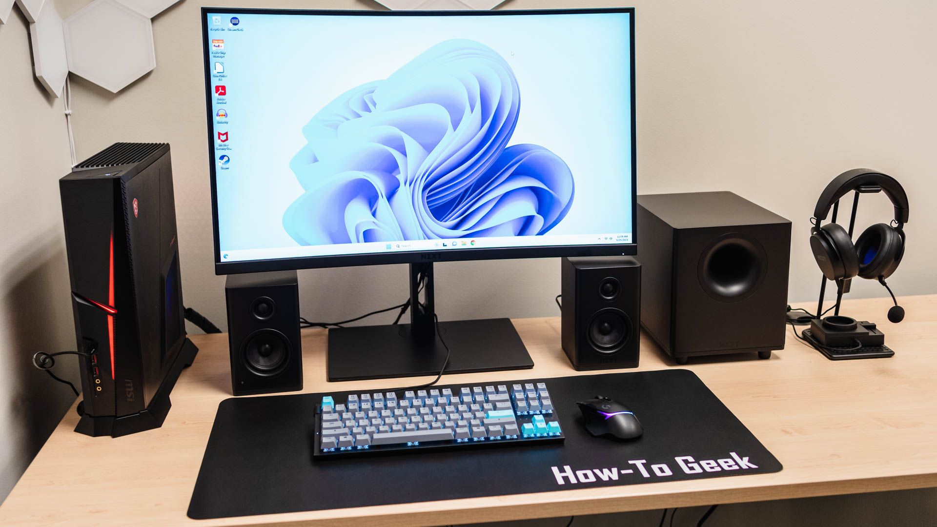 A desk set up with a NZXT Relay Subwoofer, a set of NZXT Relay Speaker, the NZXT Relay Headset, and the NZXT Switch Mix