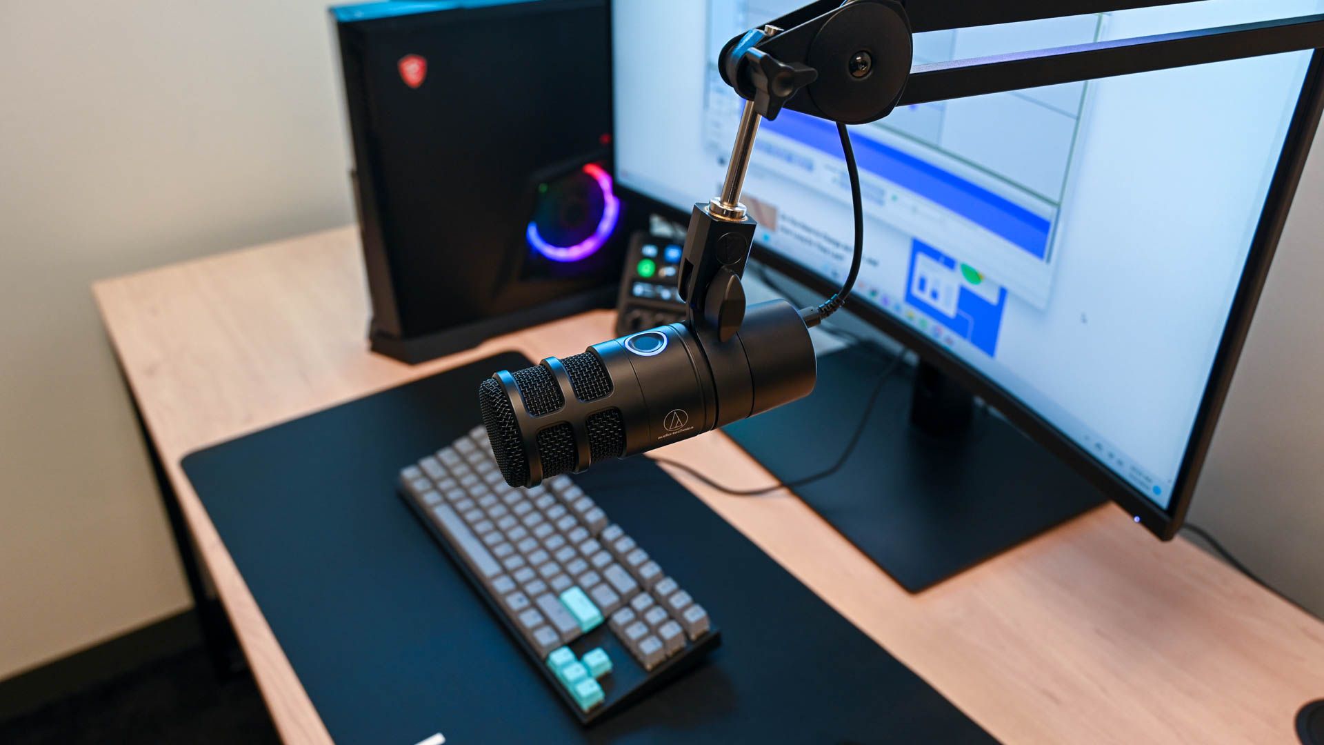 The Audio-Technica AT2040USB Microphone set up at a desk using a boom arm
