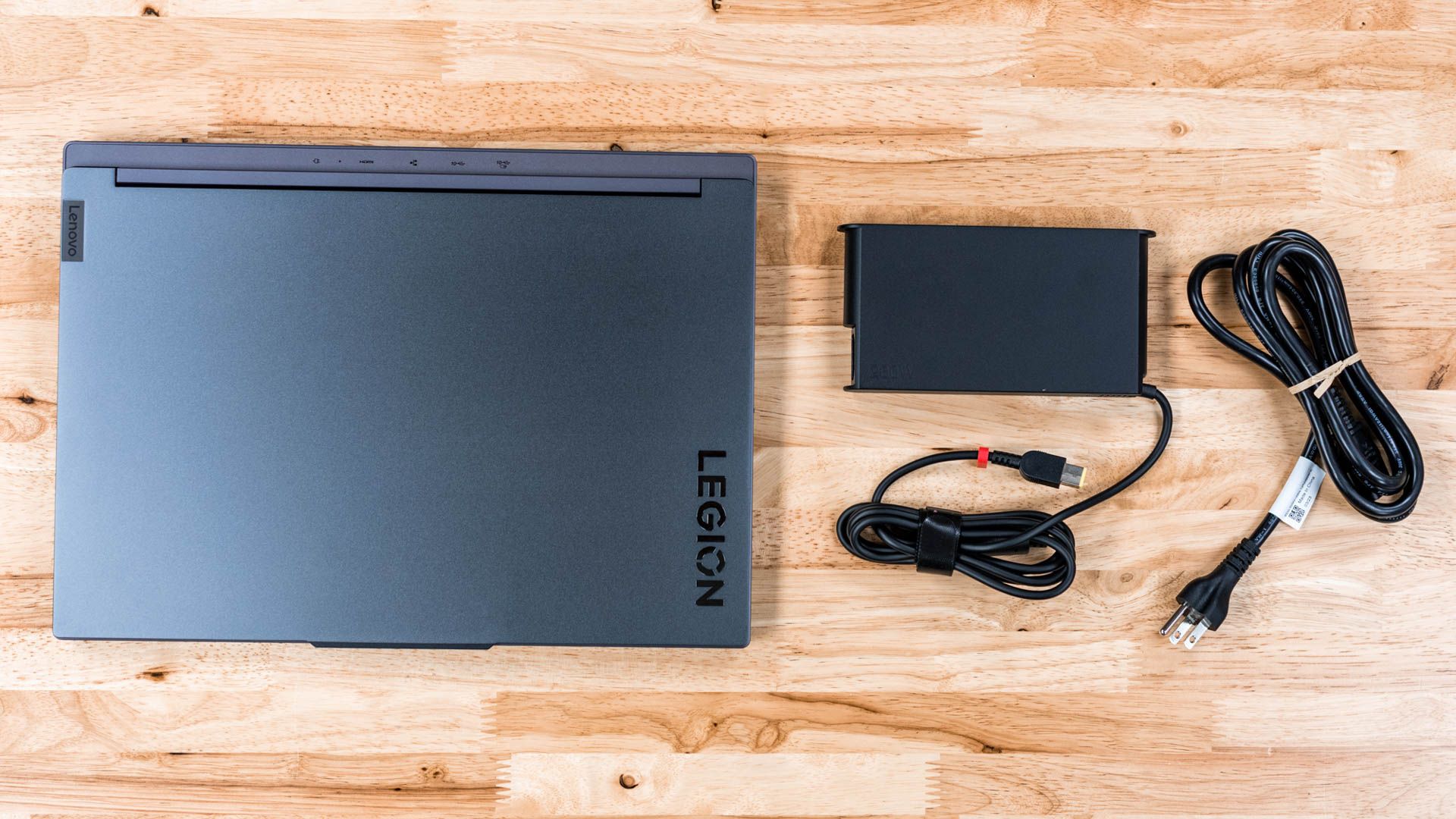 Lenovo Legion Slim 5 Gen 8 sitting on a table next to the power adapter