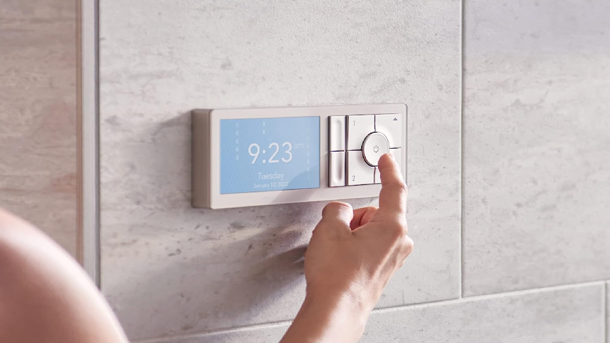 Woman adjusting shower settings with a wall-mounted Moen Smart Shower Controller.