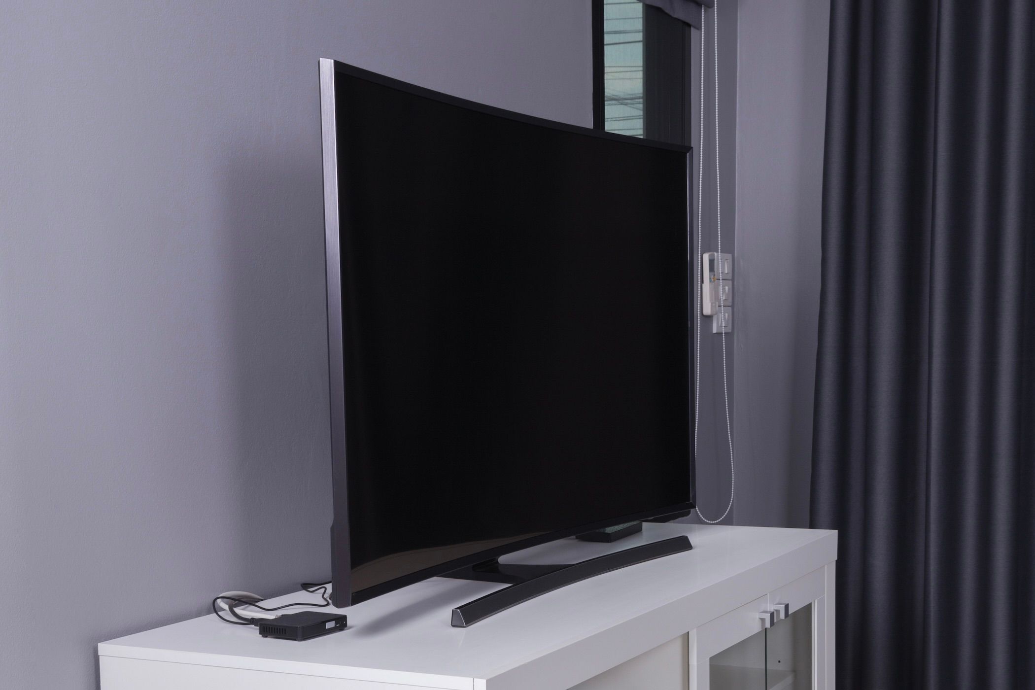 Curved LED TV on a white stand.