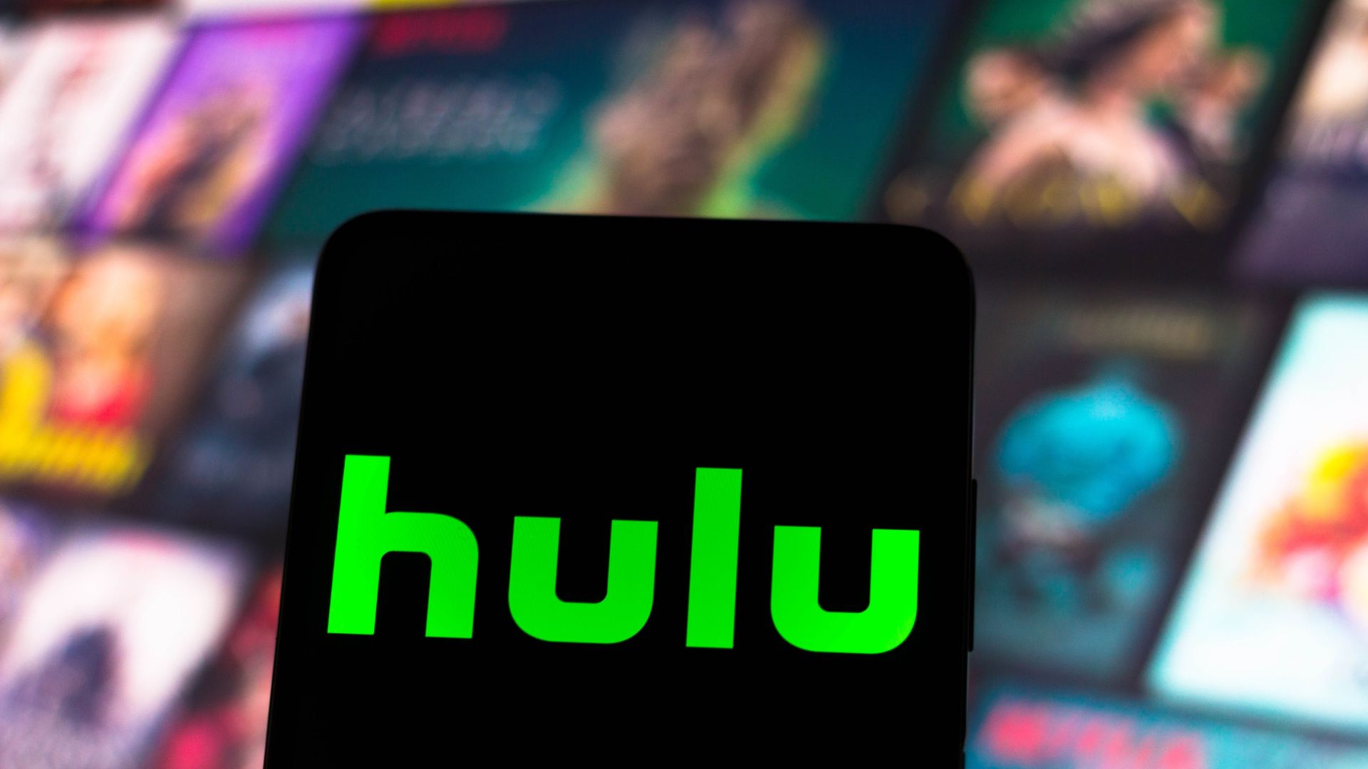 Hulu logo on a smartphone in front of a smart TV. 