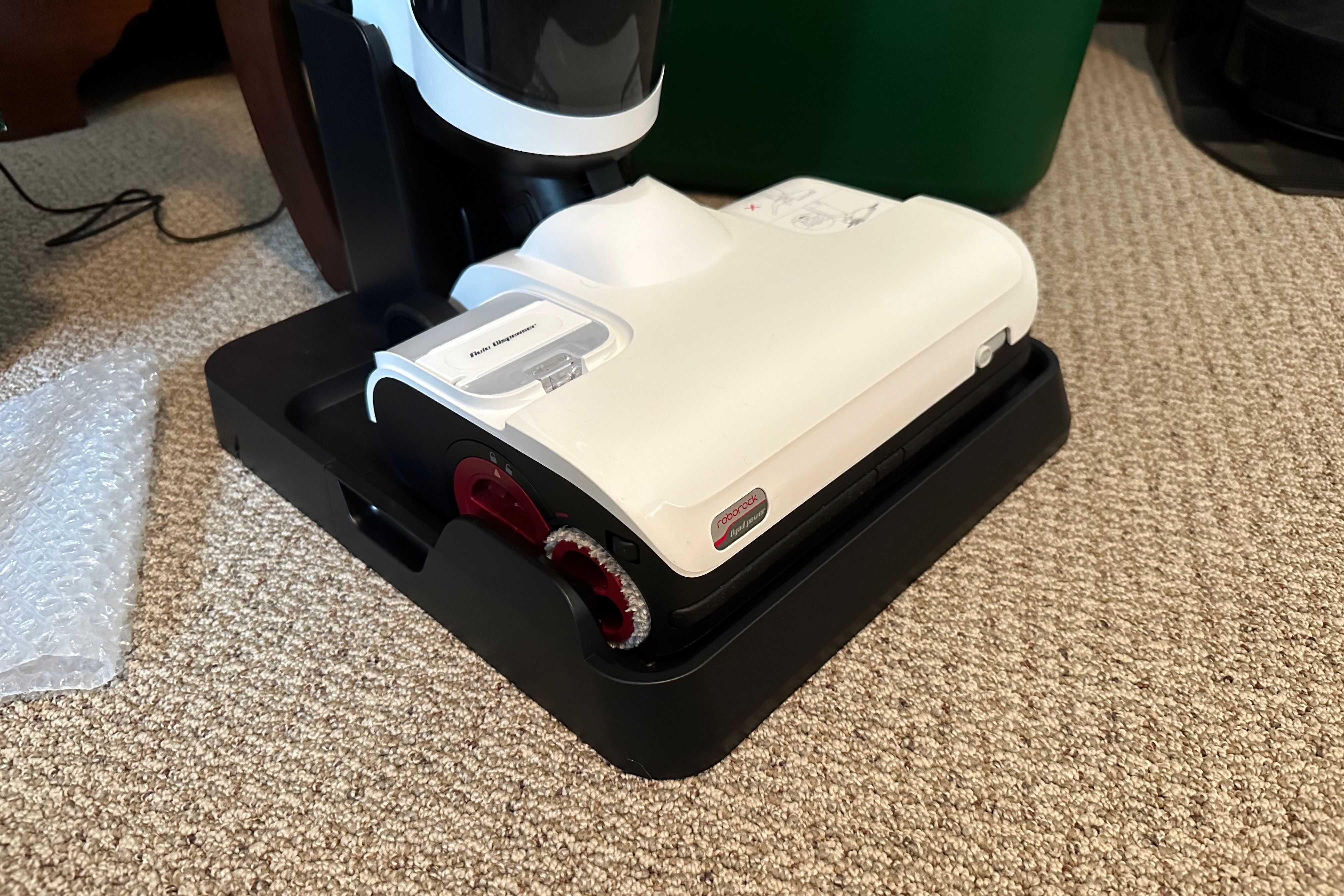 Shows the Roborock Dyad Pro in its charging dock on a carpeted floor