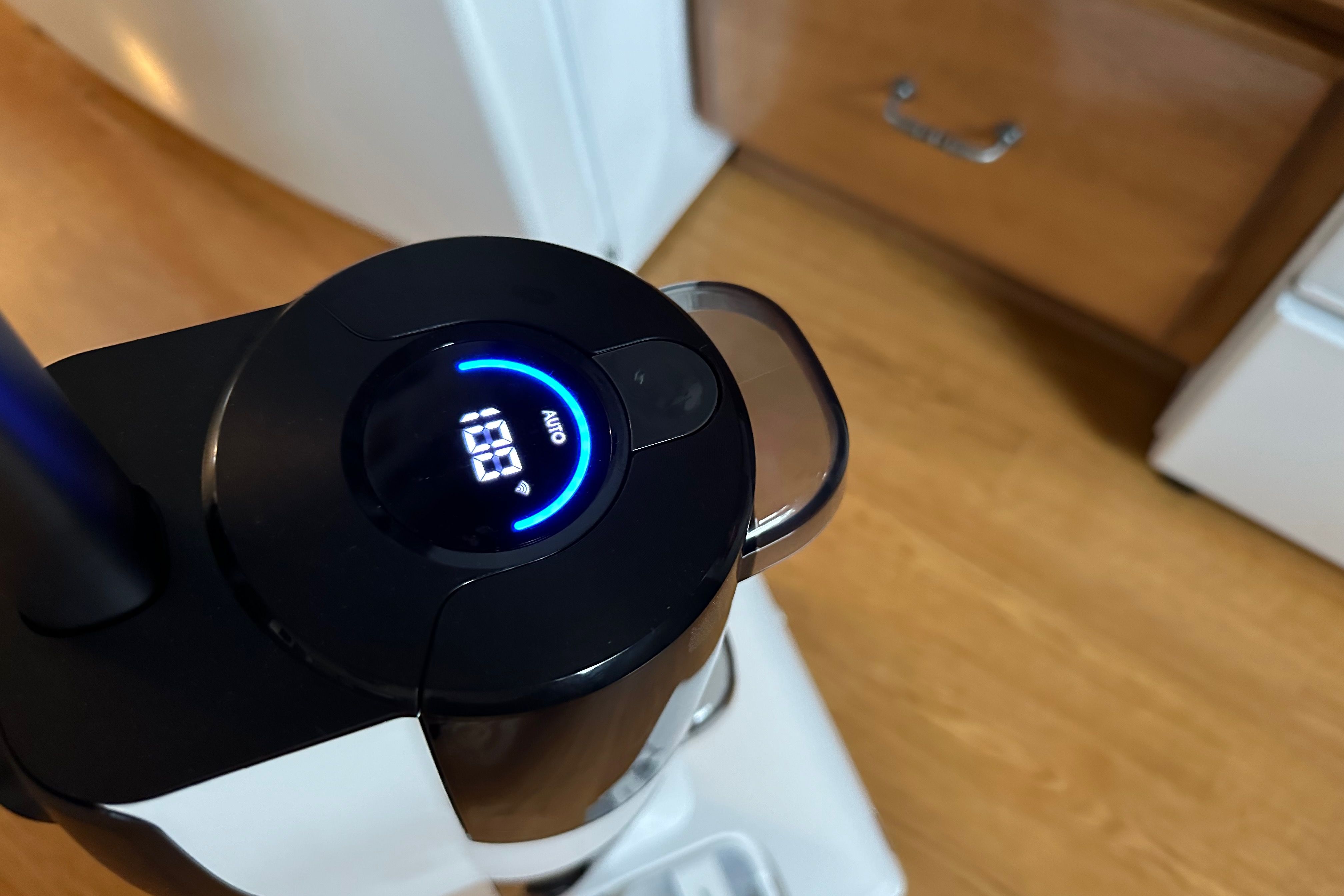 Showing a closeup of the Roborock Dyad Pro's LED with the machine standing upright in a kitchen on hardwood floor