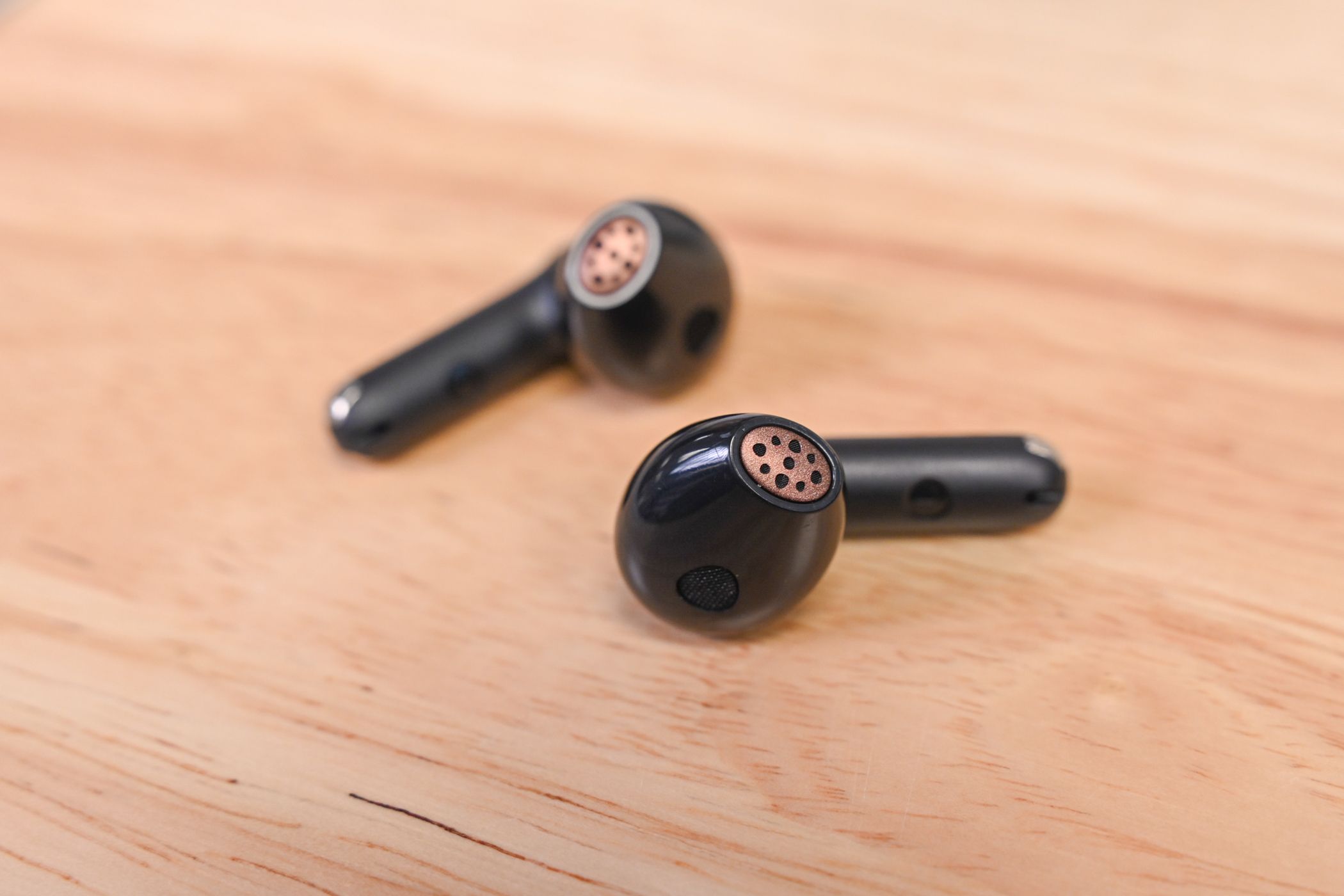 OUNDPEATS Air4 aptX Lossless Wireless Earbuds laid on a wood desk