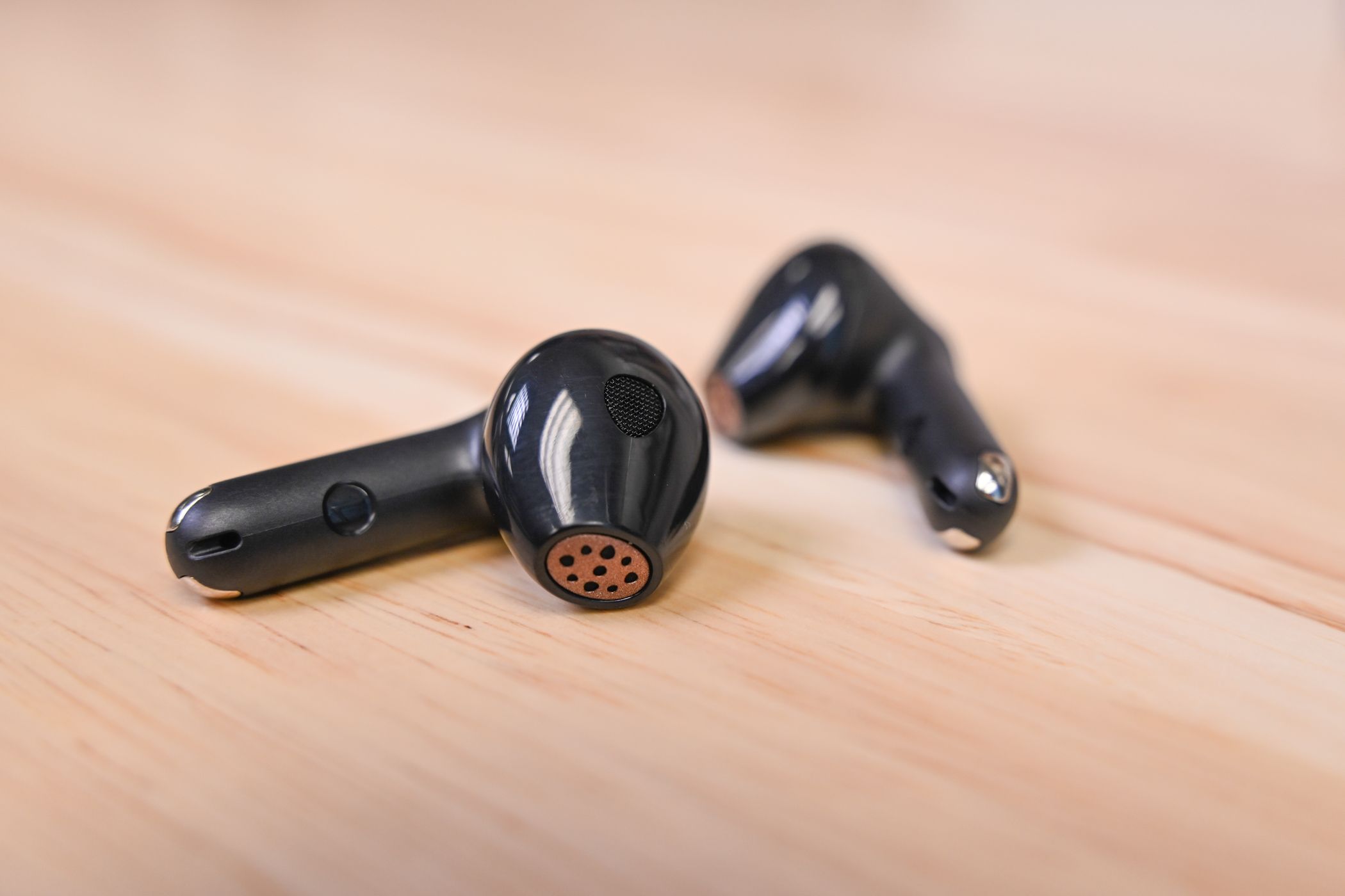 Alternate angle of the SOUNDPEATS Air4 aptX Lossless Wireless Earbuds laid on a wood desk