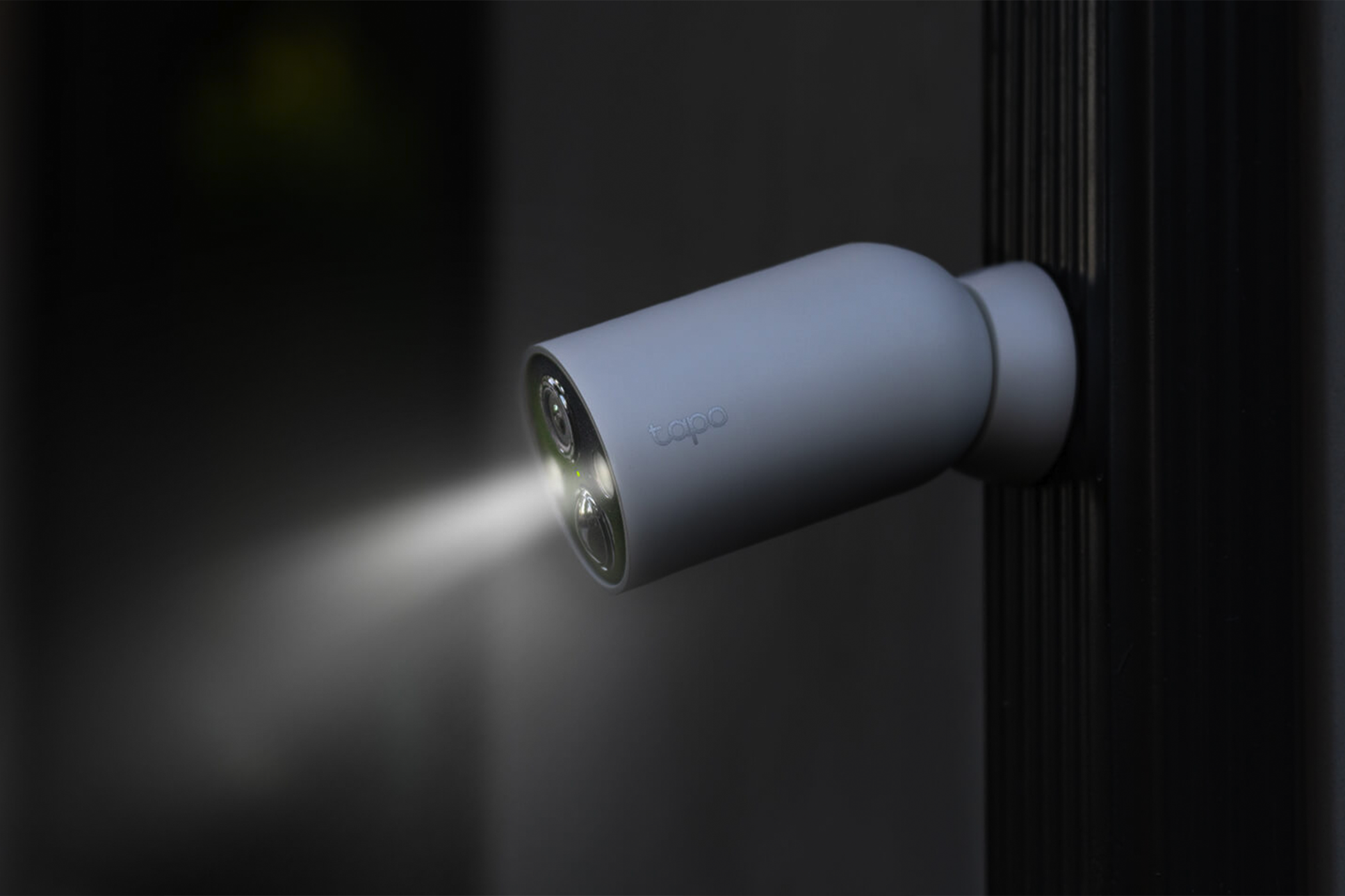 The TP-Link Tapo Wire-Free Security Camera shining its built-in spotlight at night.