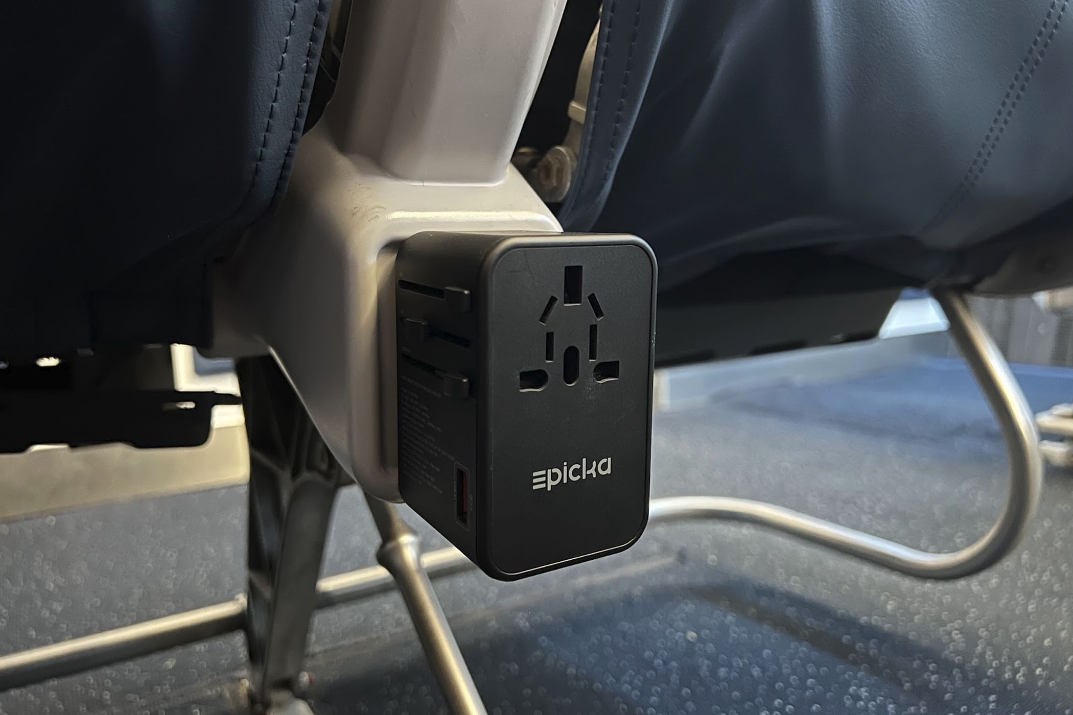 An international power adapter plugged into a Delta Airlines plane