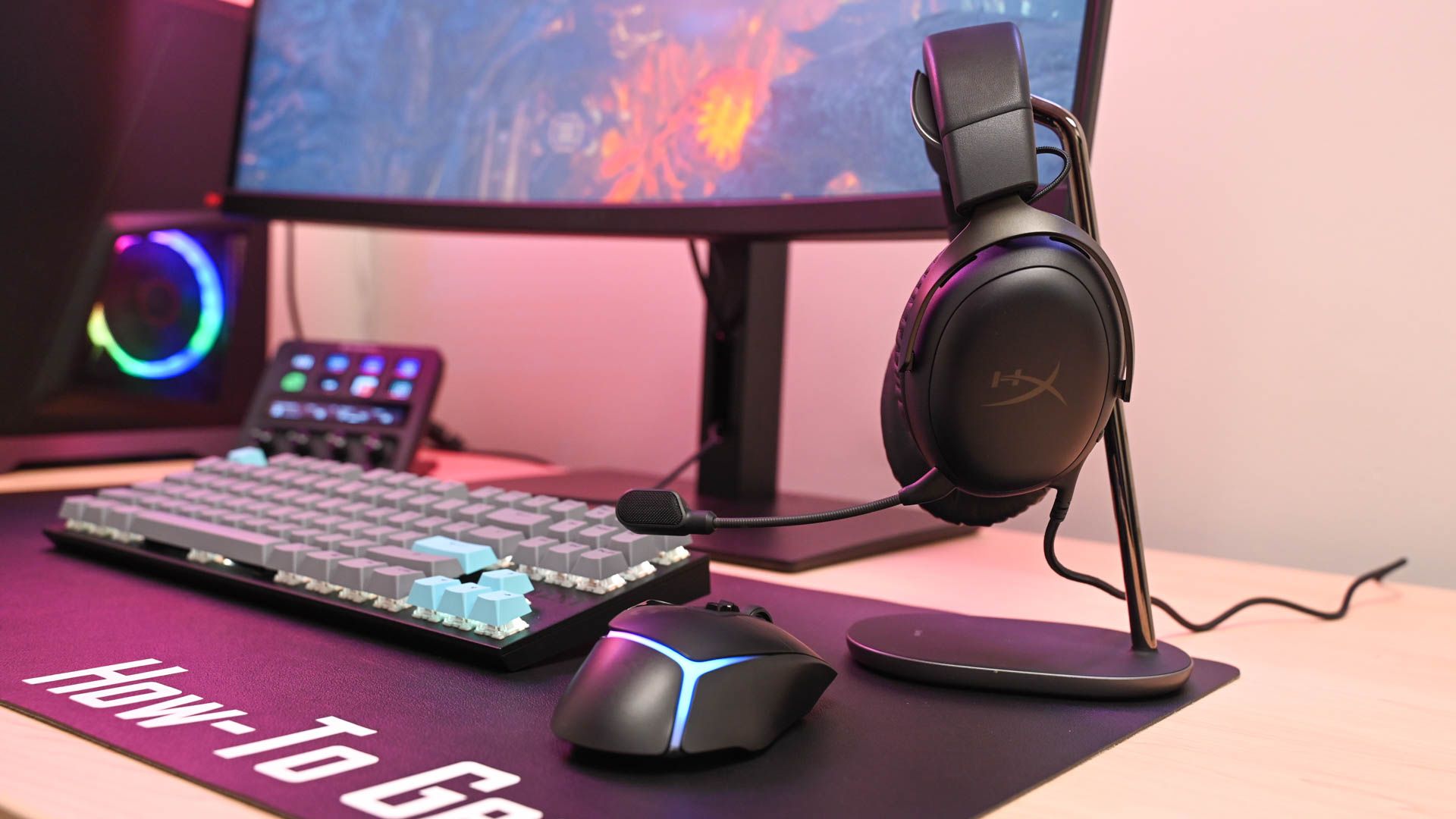 The HyperX Cloud III on a headphone stand infront of a gaming PC