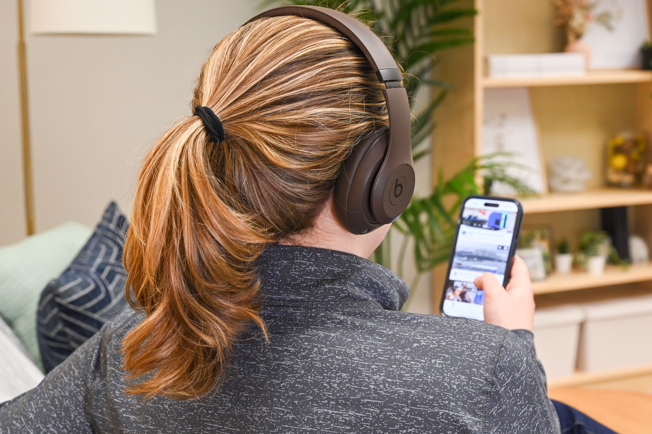 Person wearing a pair of Beats Studio Pro while watching videos on an iPhone