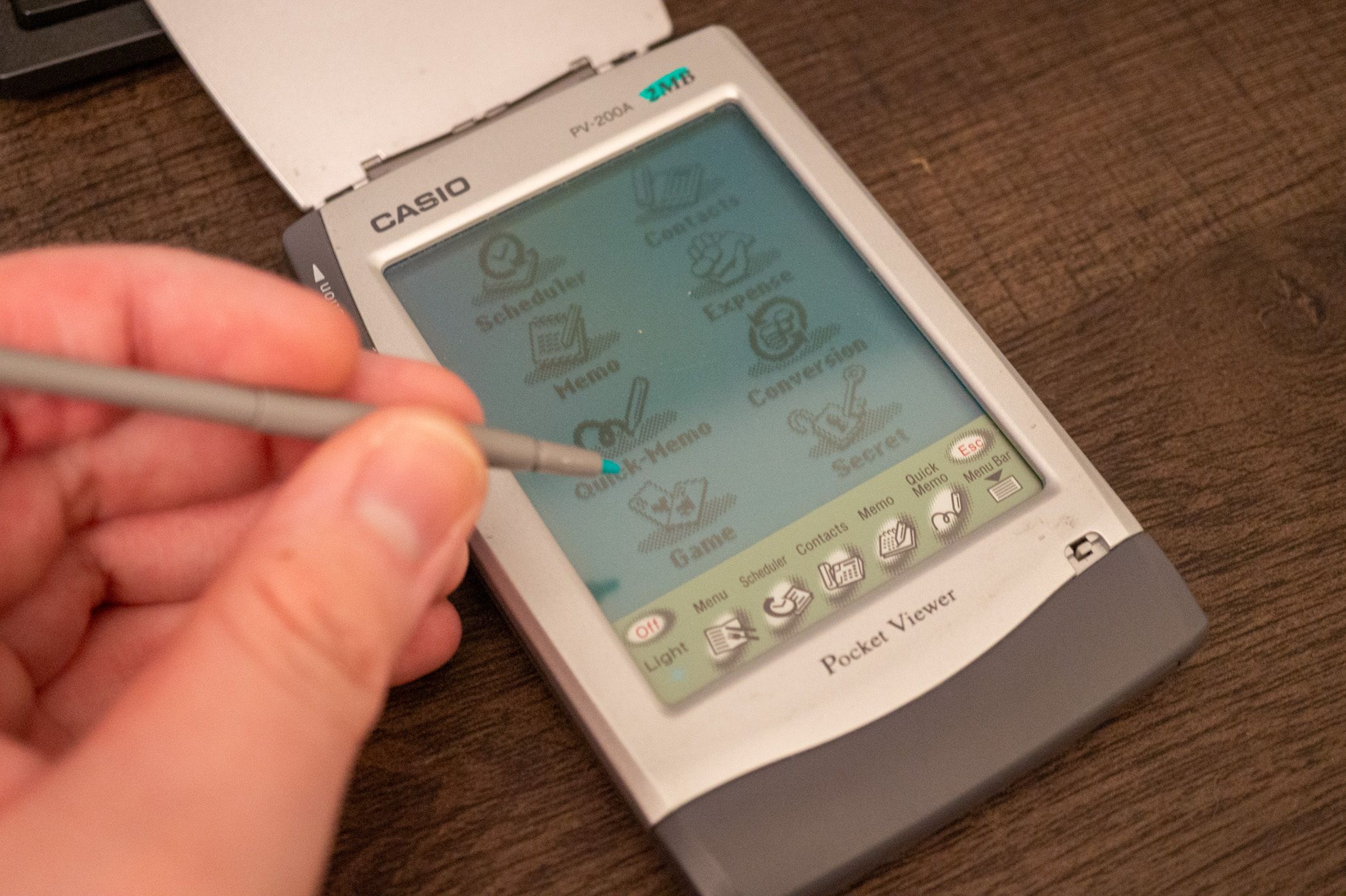 Person using a stylus on an old Casio Pocket Viewer PDA.