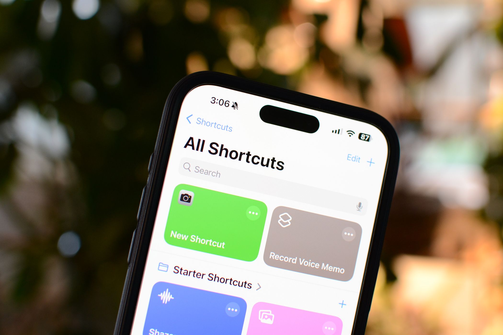 An iPhone 15 Pro Max with the iOS Shortcuts app open.