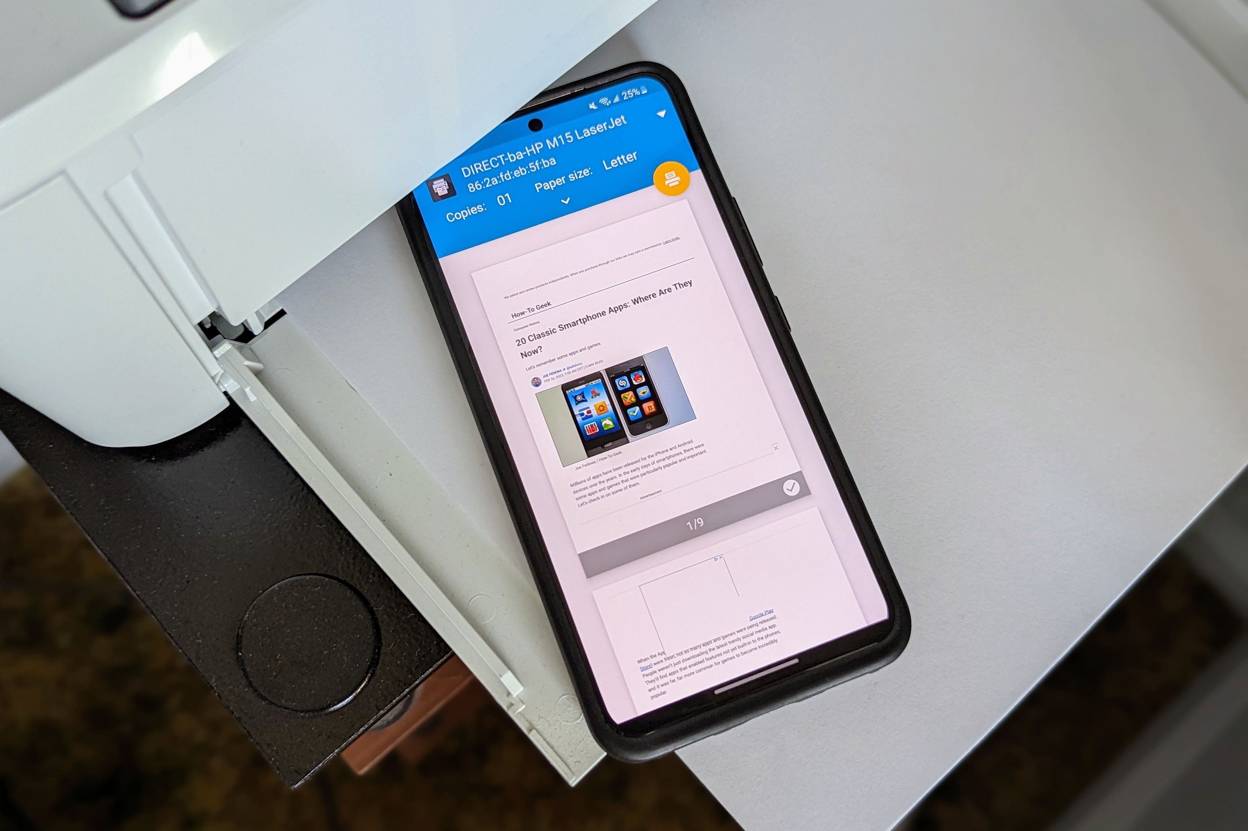 An Android phone sitting on top of a printer paper tray.