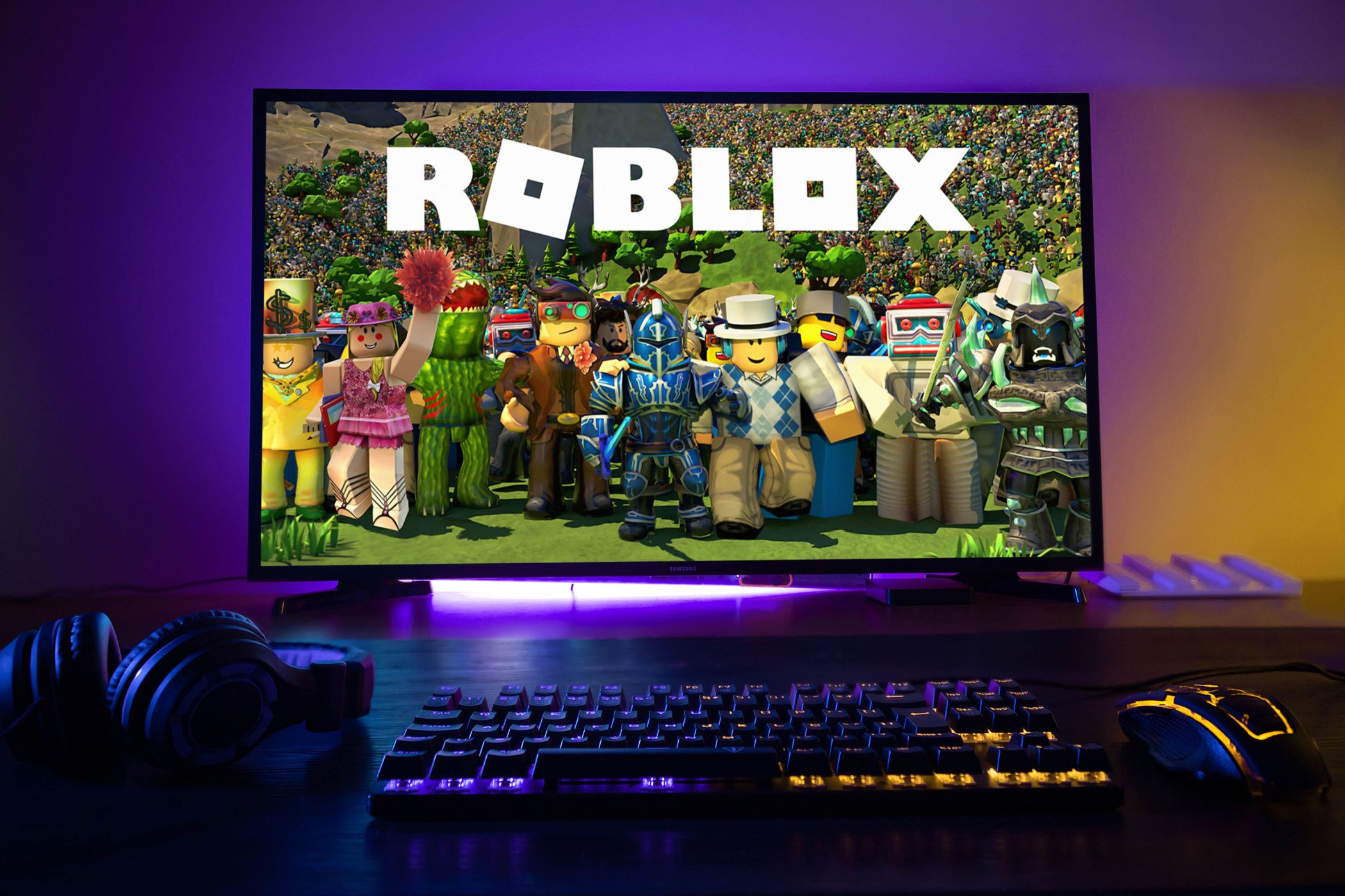 Roblox visible on a PC screen with LED backlight, keyboard, and mouse.