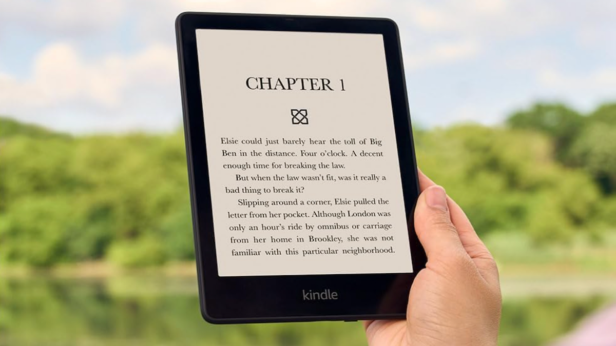 Hand holding up an Amazon Kindle Paperwhite to read an e-book.