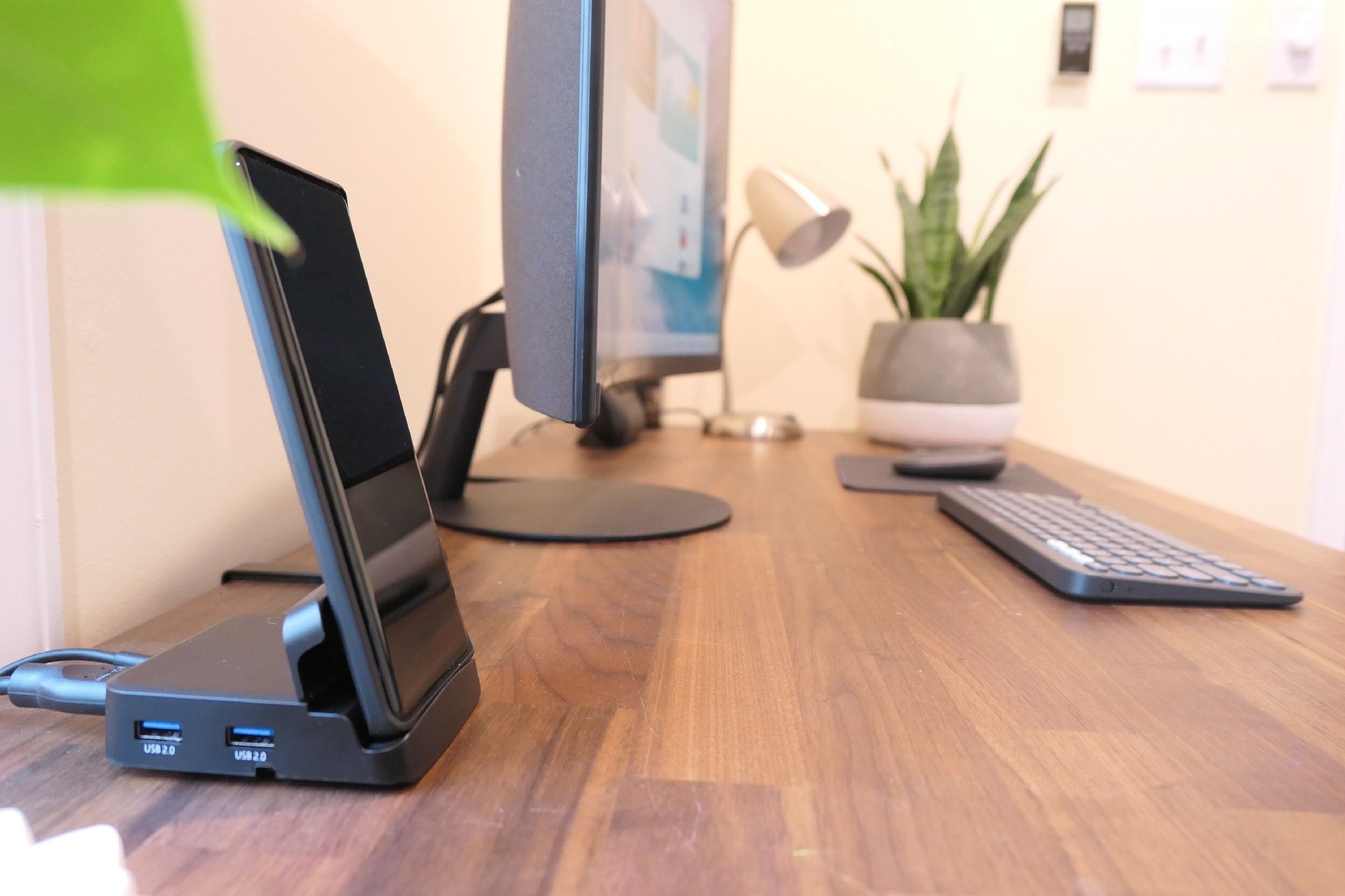 An Android phone docked next to a curved monitor.