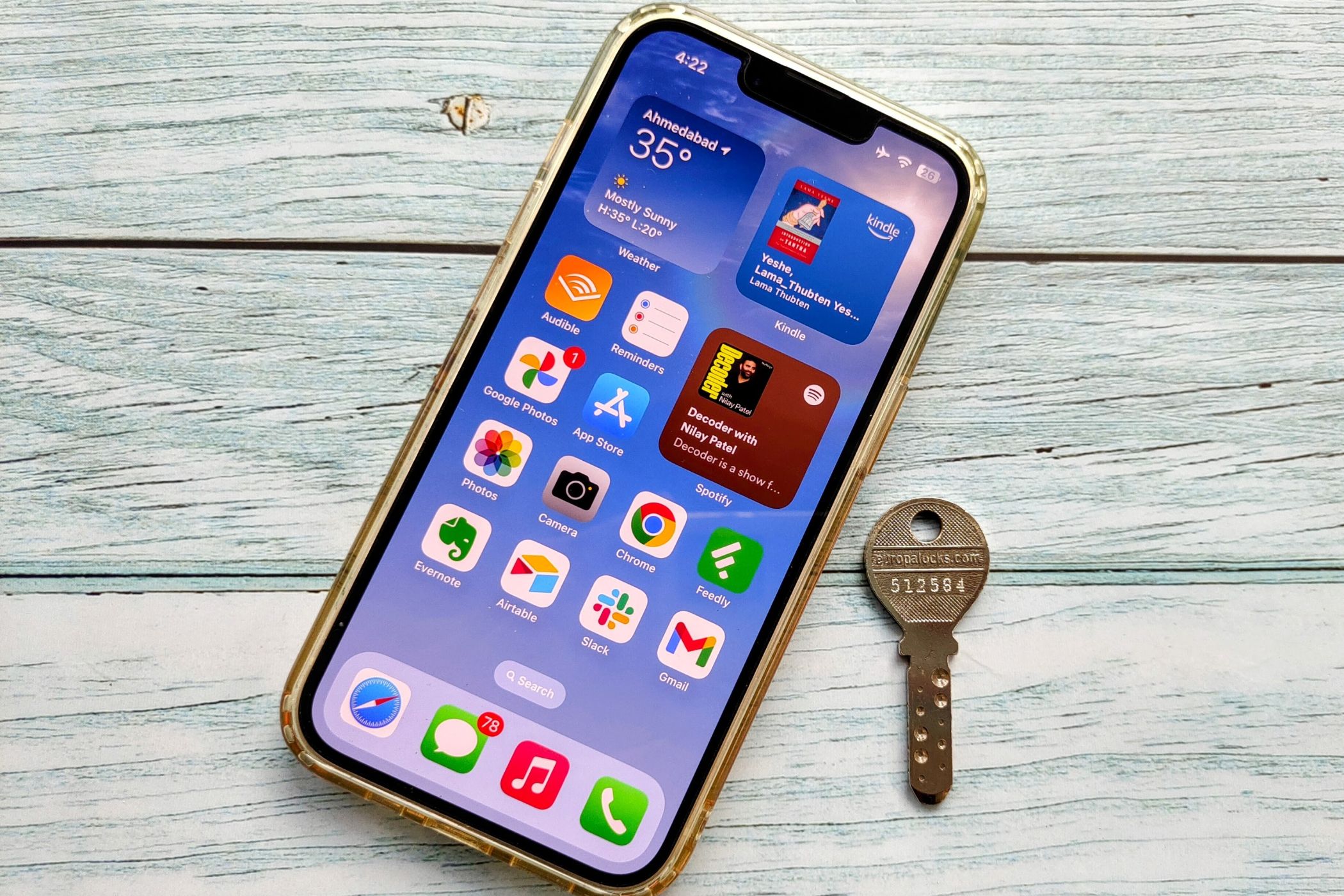 An iPhone lying on a flat surface next to a key.
