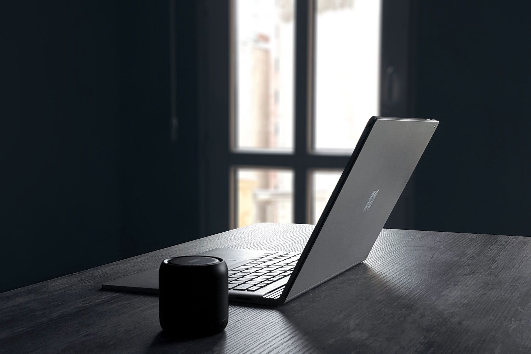 A Windows laptop next to a Bluetooth speaker on a table