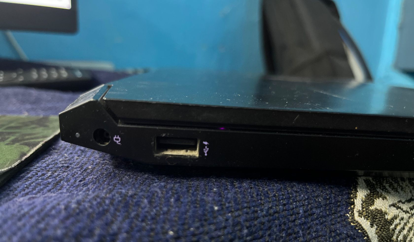 Charging port on a laptop with visible dust surrounding it.