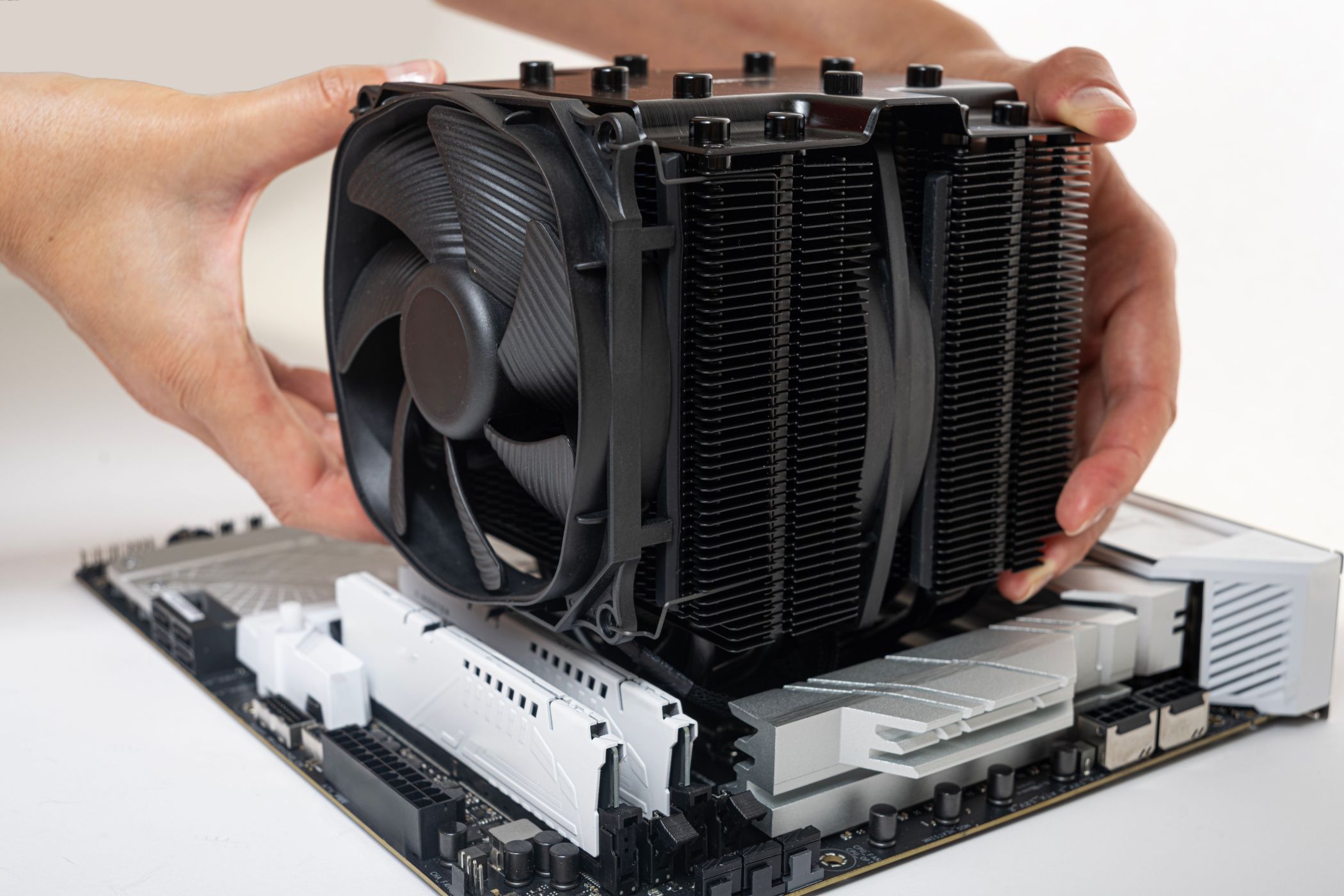 A large air CPU cooler is being installed onto a motherboard.
