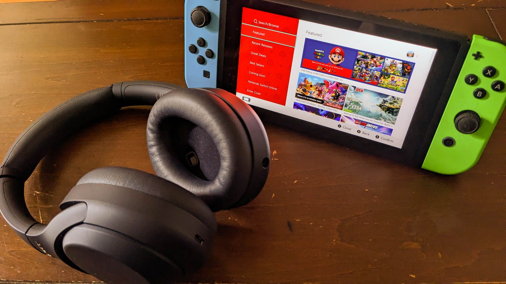 A Nintendo Switch standing up next to a pair of Sony XM4 headphones