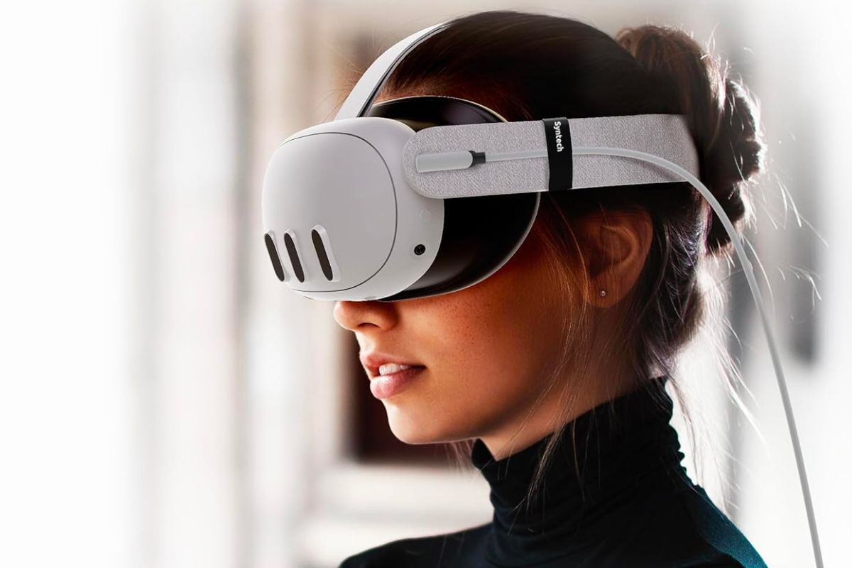 A woman wearing a Quest 3 VR headset with a Syntech cable plugged into it.