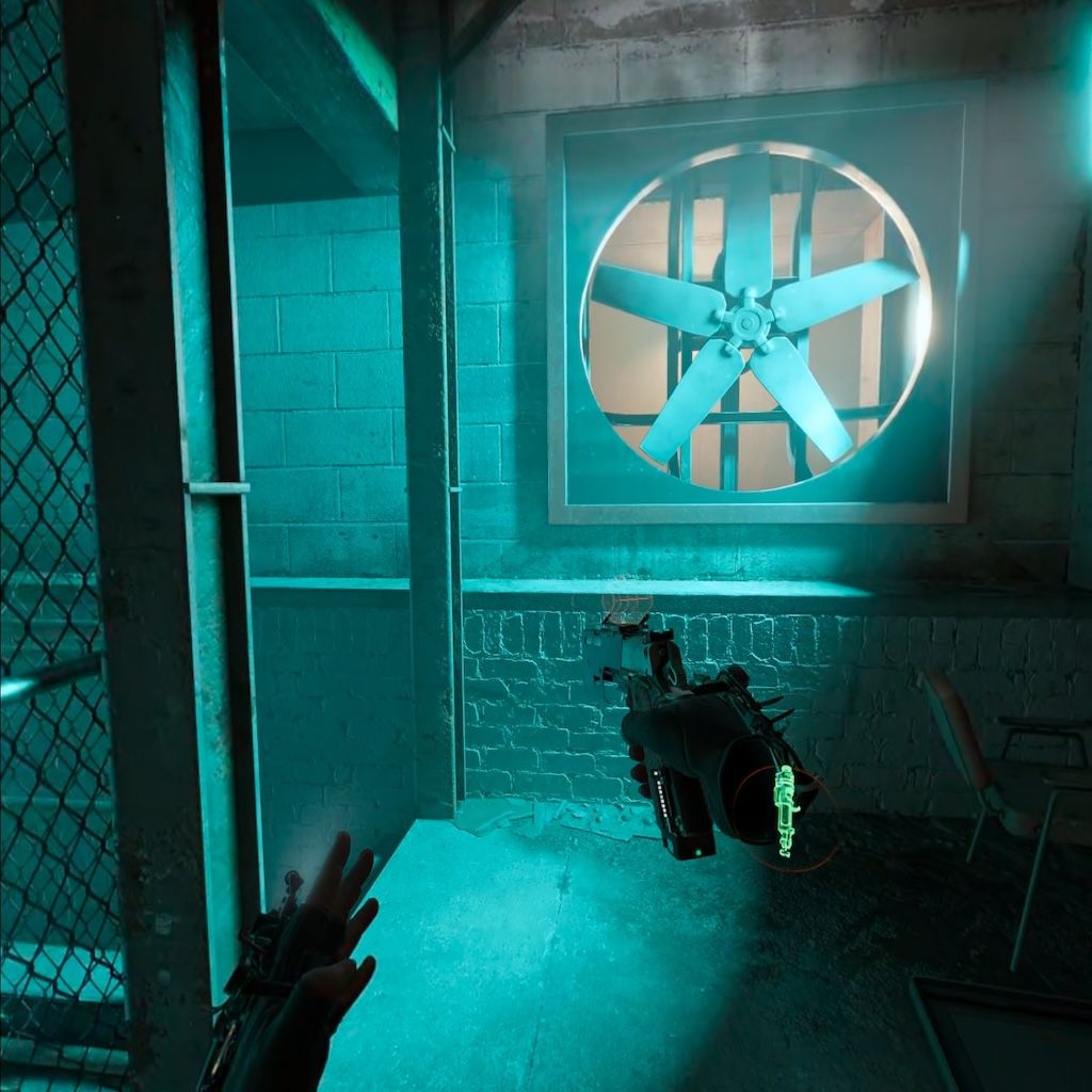The player's view in Half-Life Alyx, with two hands visible, the right holding a pistol. The room is cold and bathed in blue light. There is a large ventilation fan embedded in the wall.