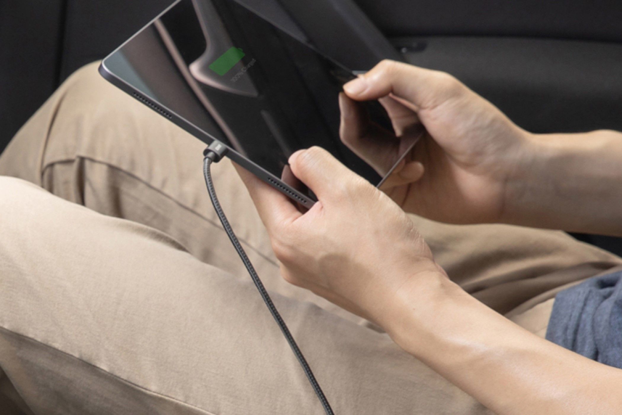 A person sitting in a car, using the Anker USB C to USB C Cable to charge their tablet