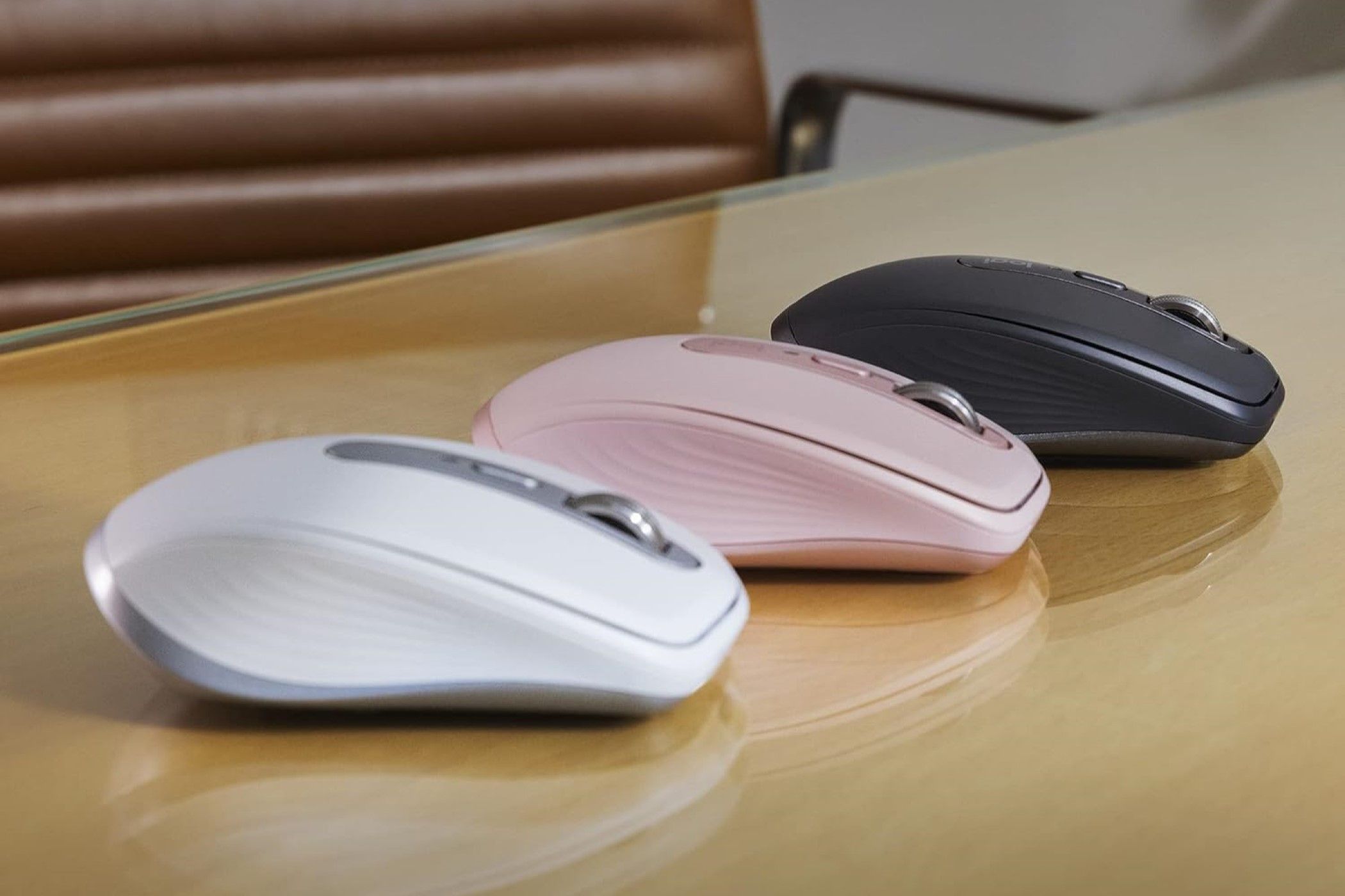 Three variants of the Logitech MX Anywhere 3S laying on a glass table