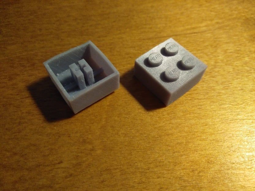 Pair of LEGO-shaped keycaps, one upside down showing the Cherry MX stem, the other showing the mounting pins