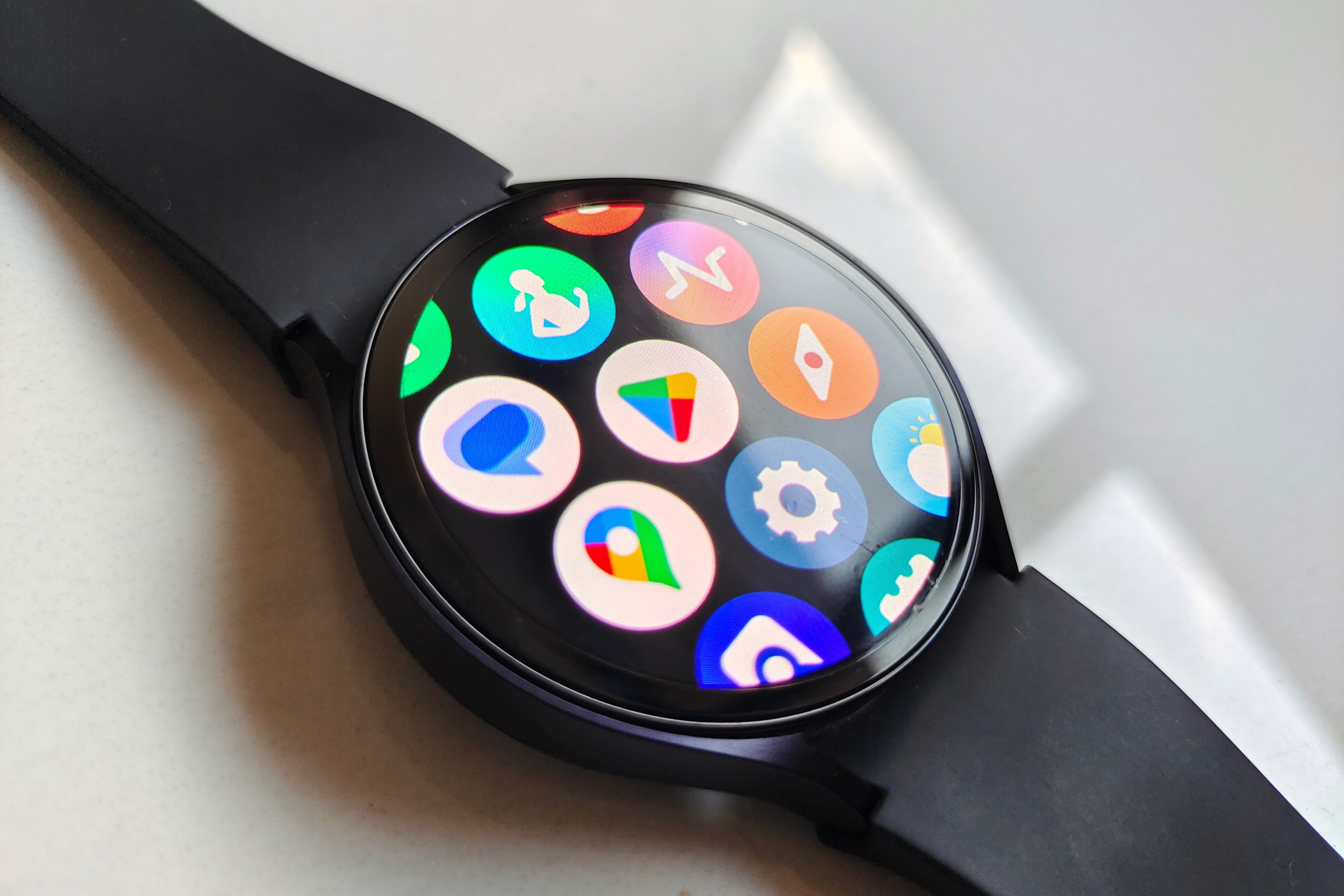 A Samsung Galaxy Watch 6 lying on a flat surface and displaying the app drawer.