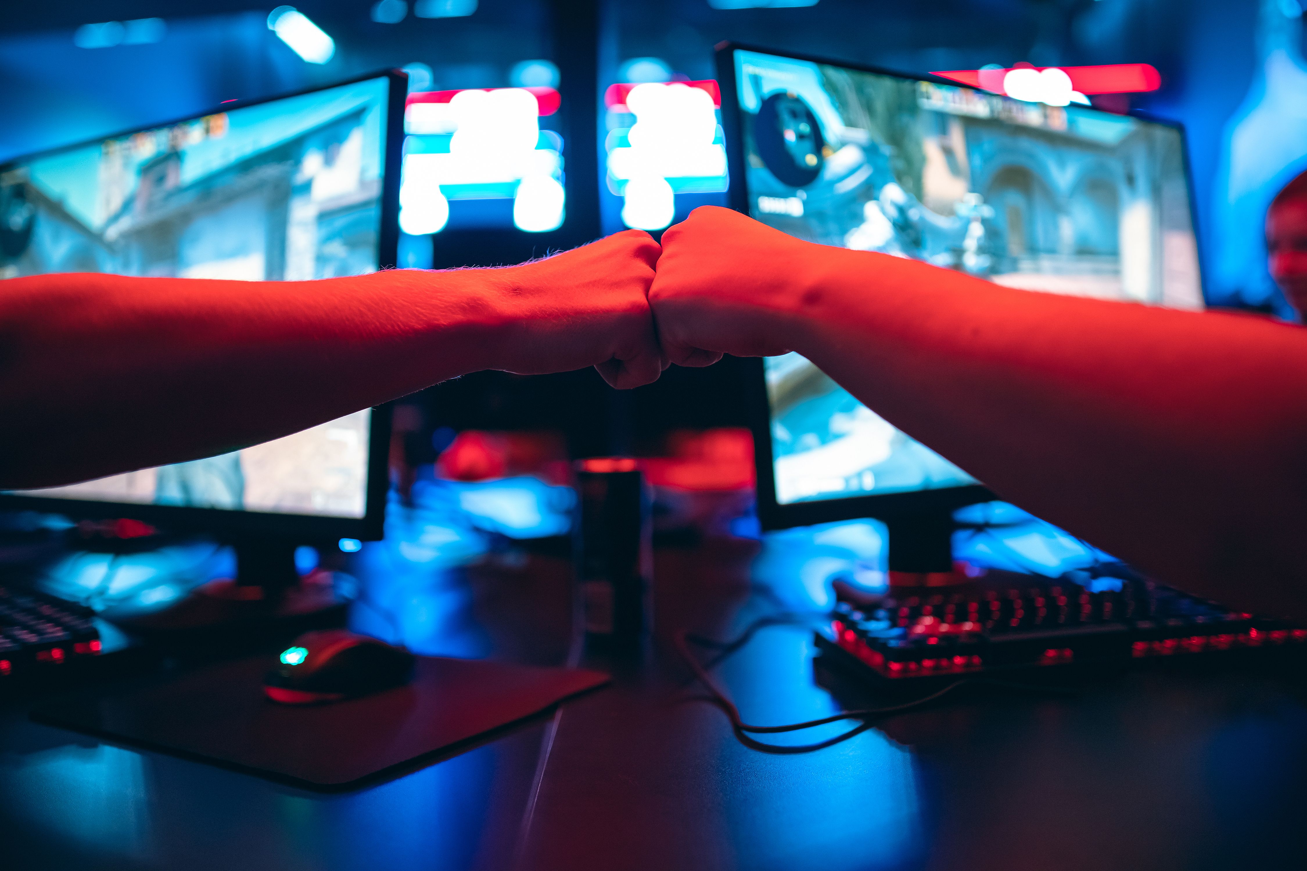 Professional gamer greeting and support team fists hands, online game in neon color, blur background. 