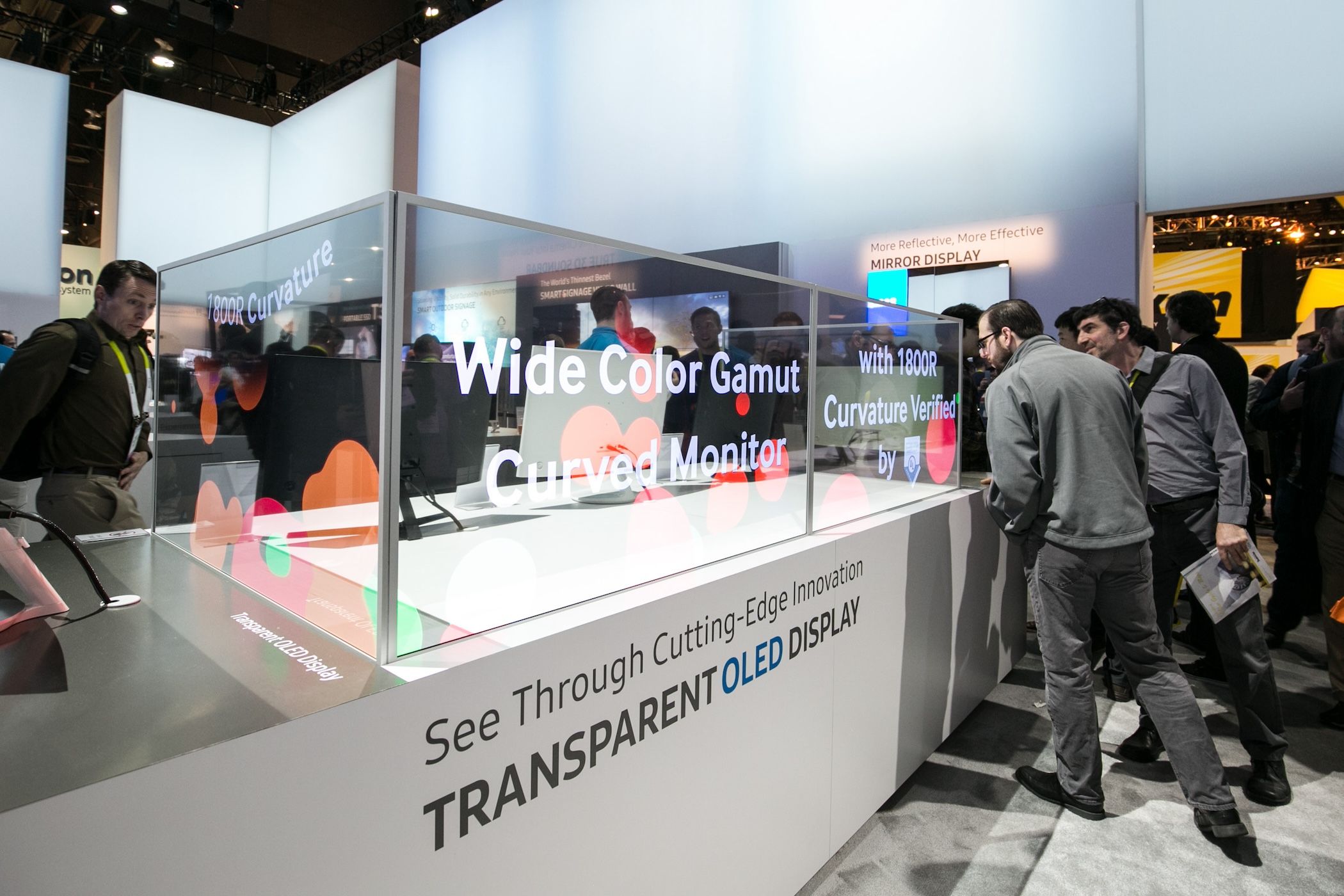 A demo kiosk showing multiple transparent OLED screens as people look on.