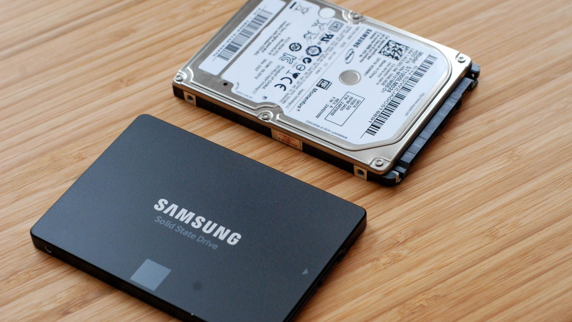 A SSD next to a small mechanical hard drive. 