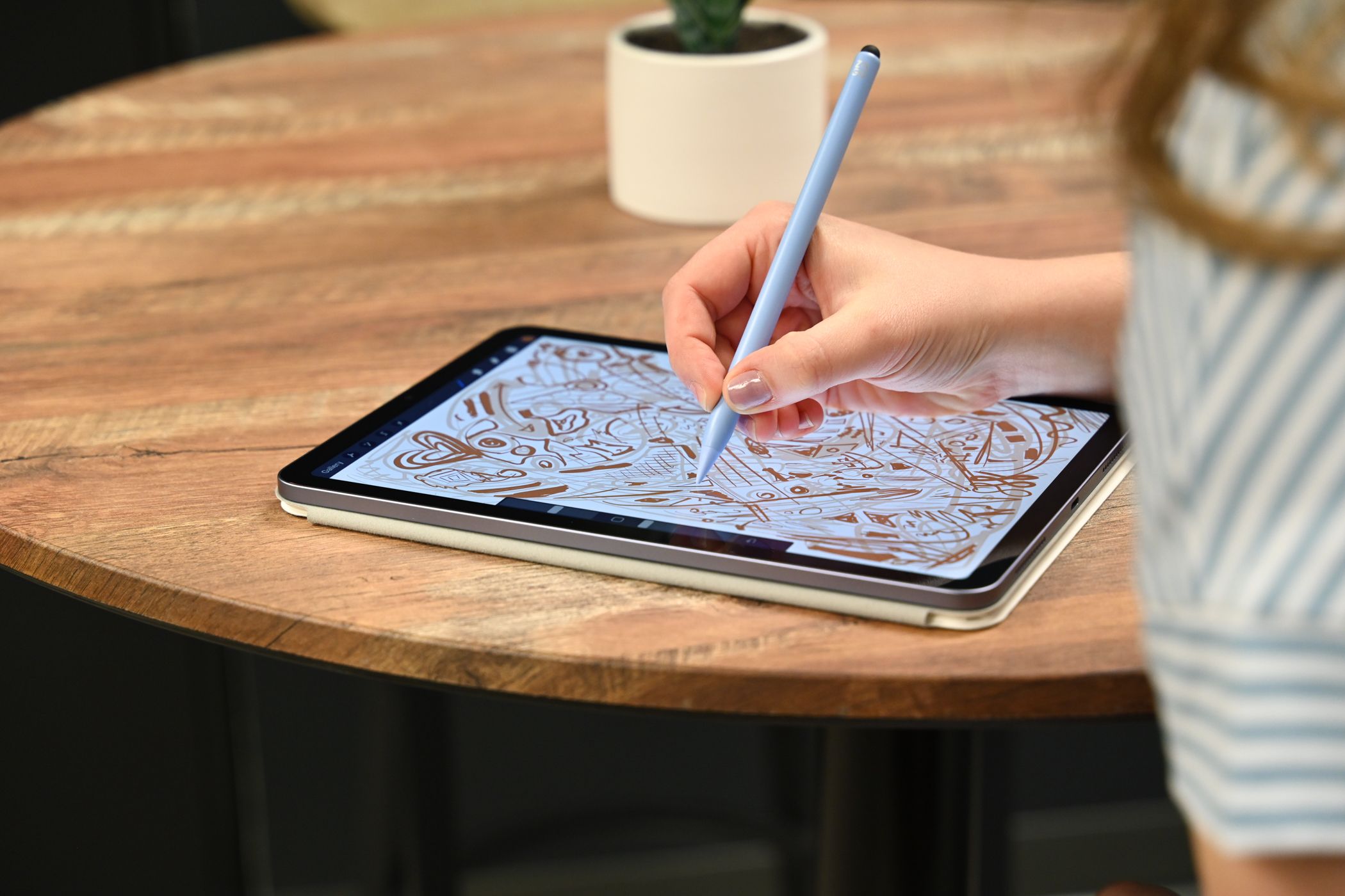 Person holding a stylus and doodling on an iPad 10th generation.