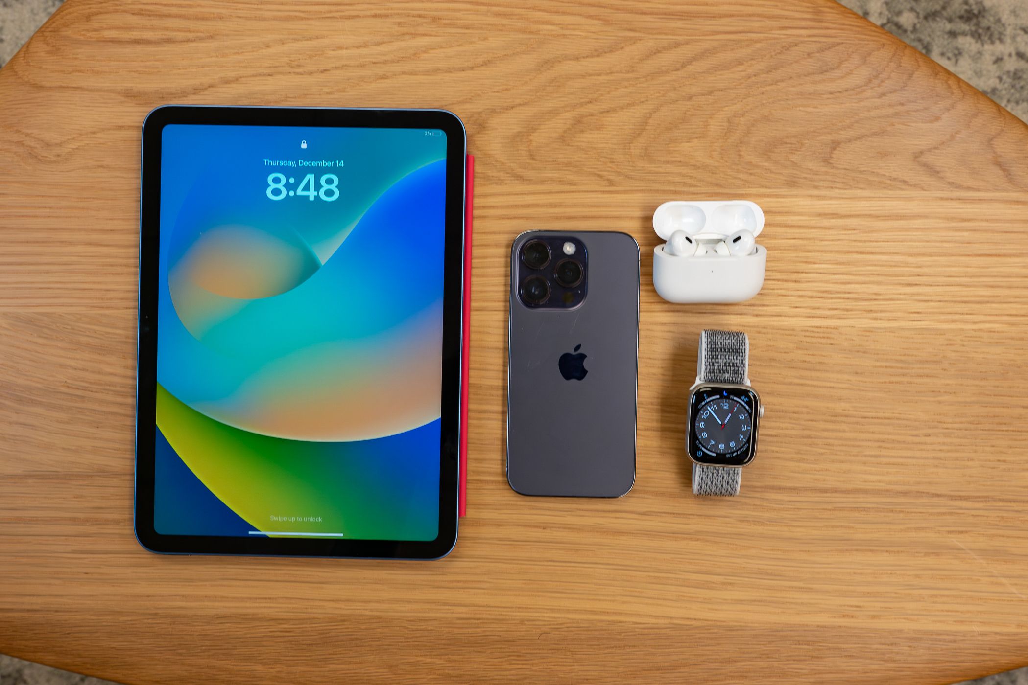 Top view of the Macbook Pro, iPhone 14, Apple watch and Airpods