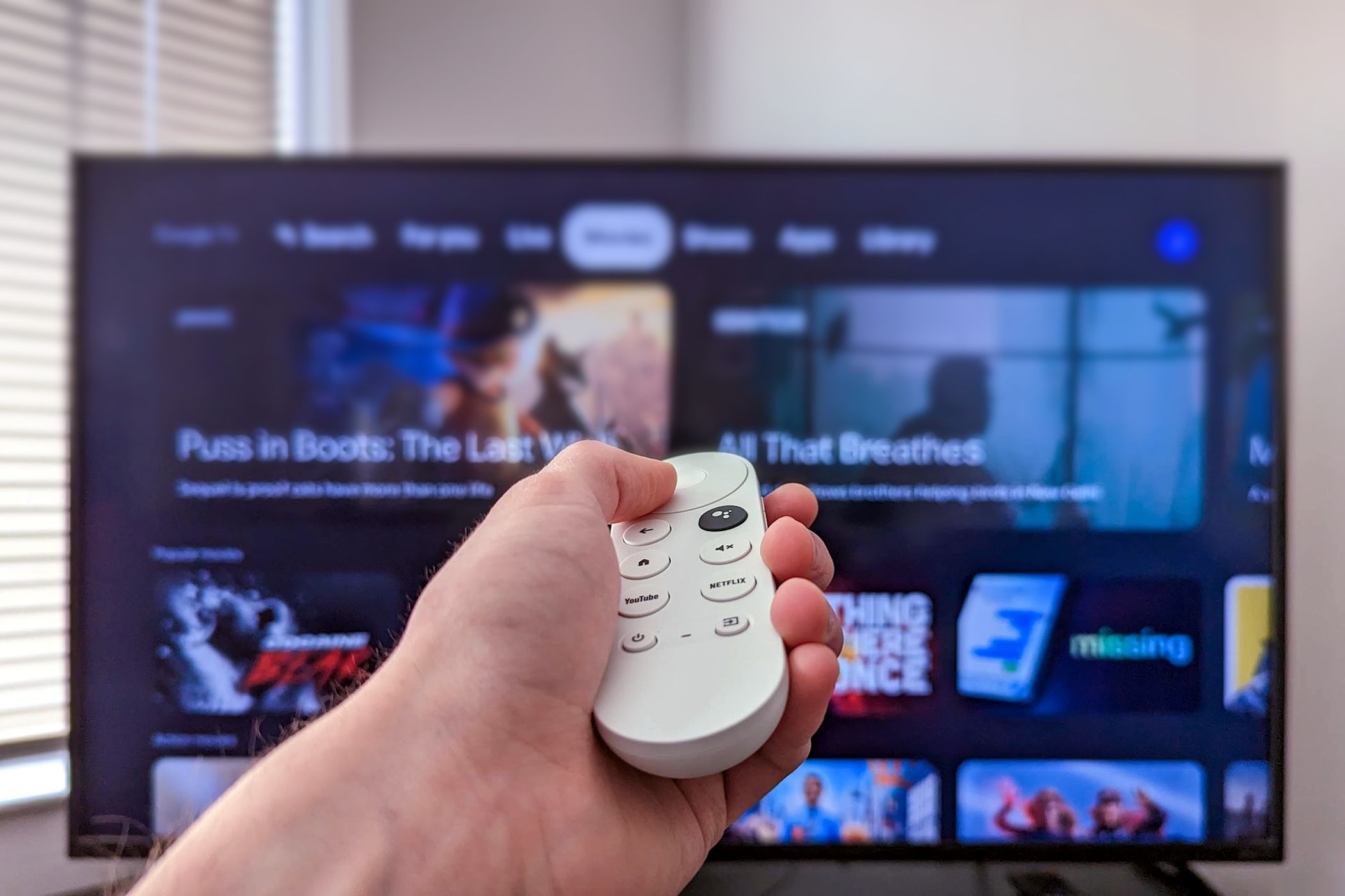 Person holding a Chromecast remote infront of a tv with Google TV open