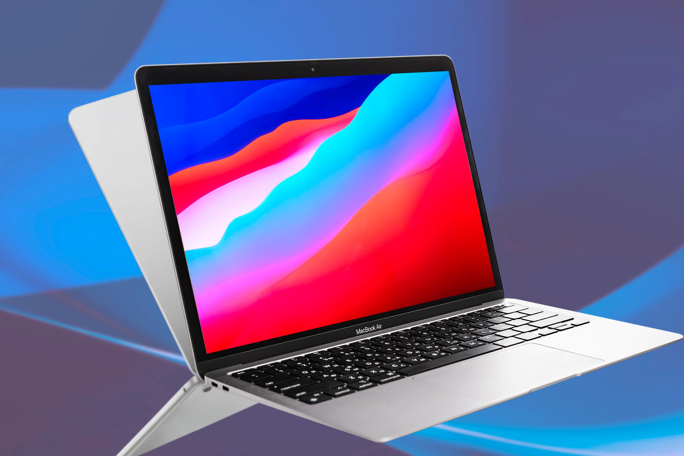 An open MacBook Air 2020 with an abstract screen and another MacBook facing the other way.