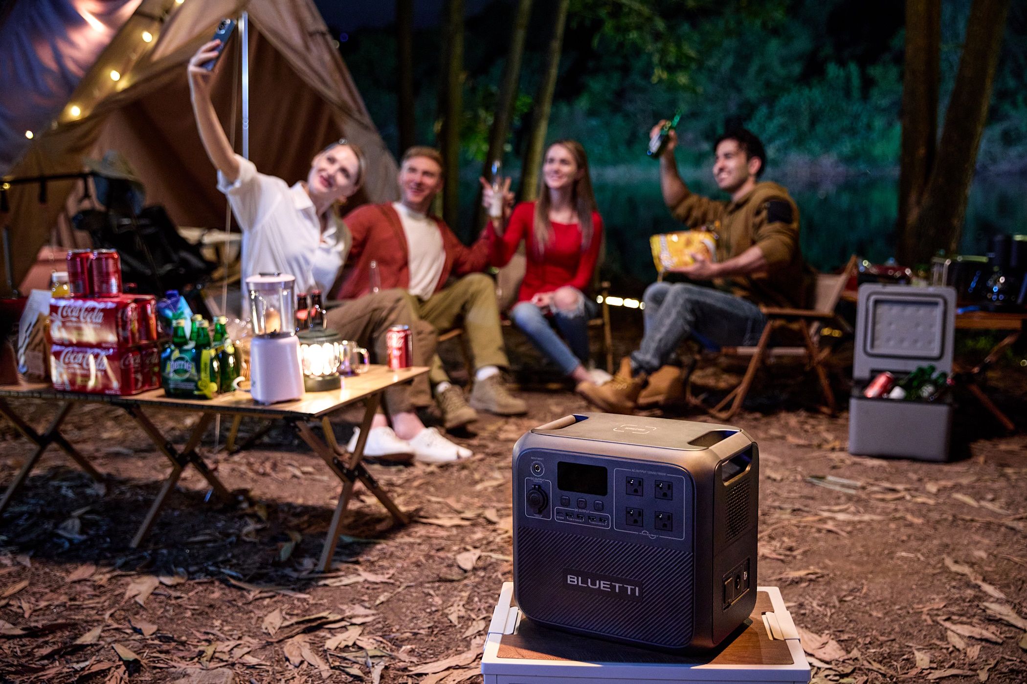 people gathered round outdoors on chairs taking a selfie with Bluetti portable power station in the foreground