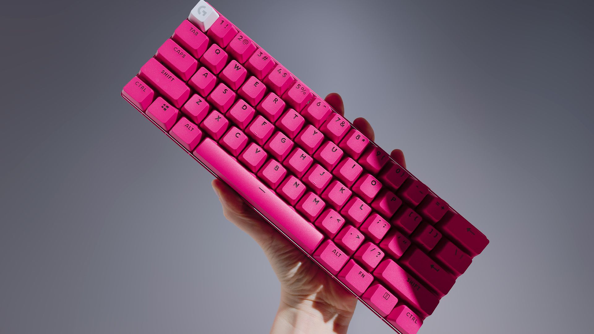 Someone holding the magenta Logitech G Pro X 60 keyboard in the air.