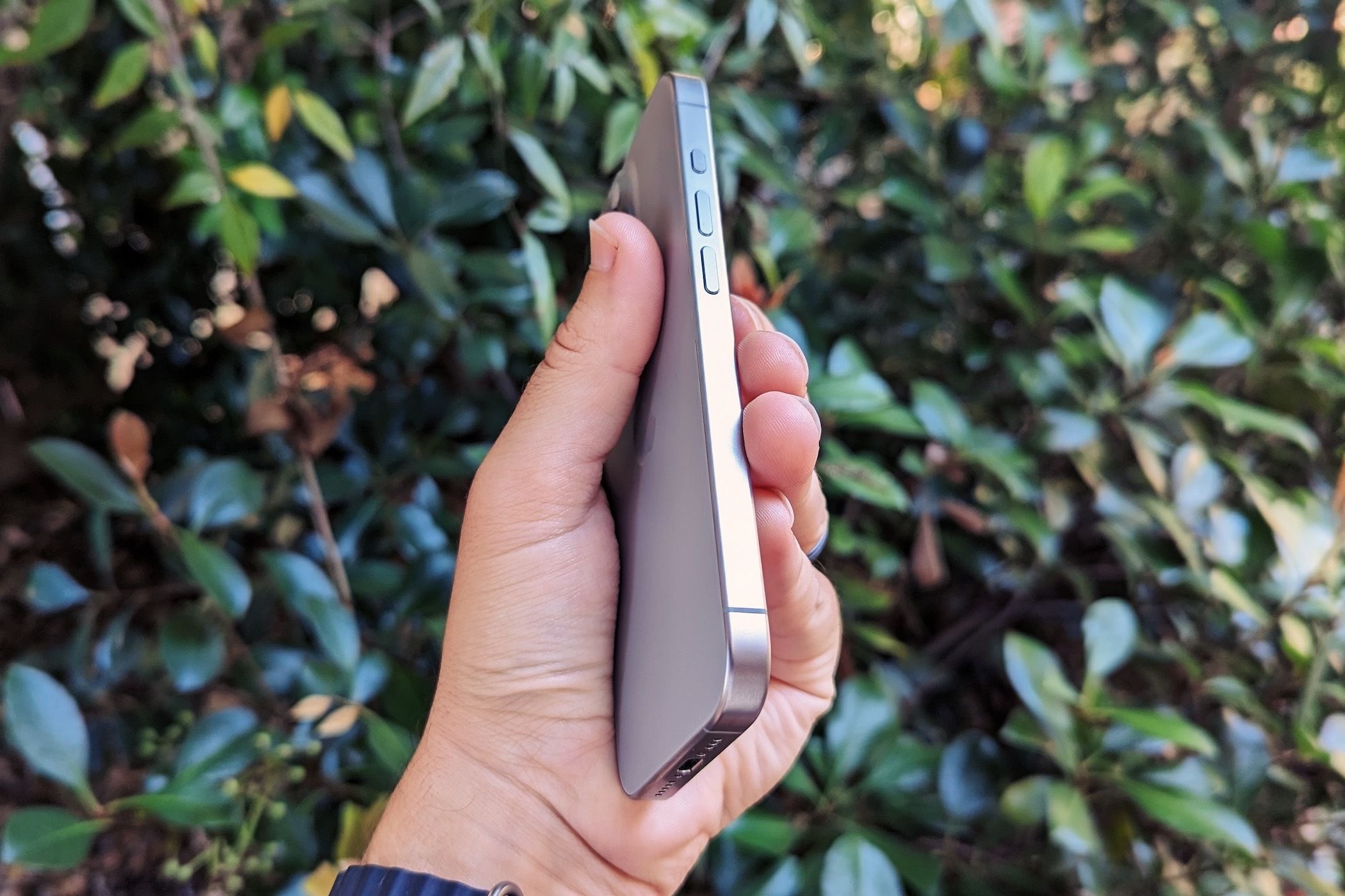 A hand holding the Apple iPhone 15 Pro showing the side buttons