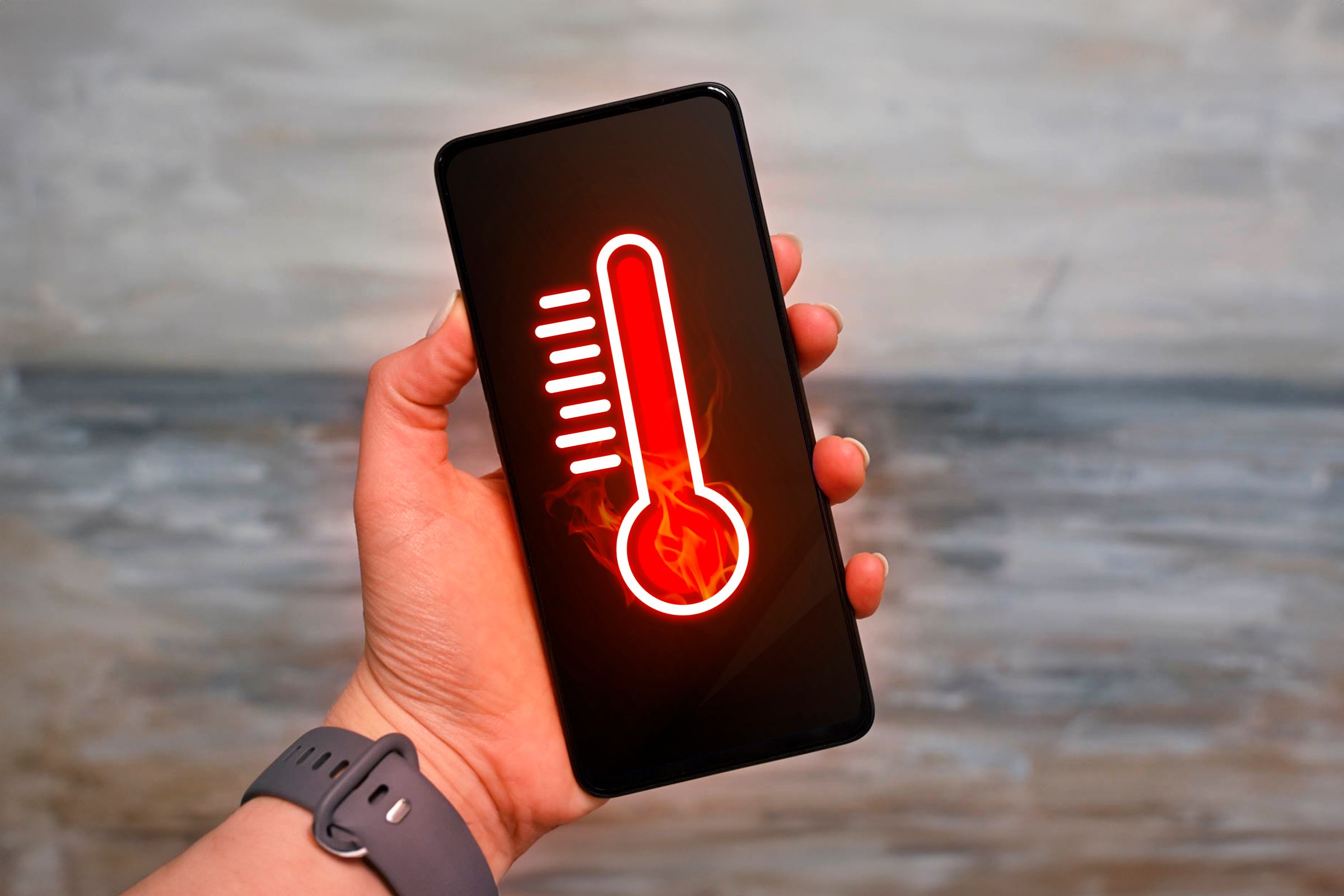A hand holding a smartphone with a thermometer, indicating that the device is overheating.